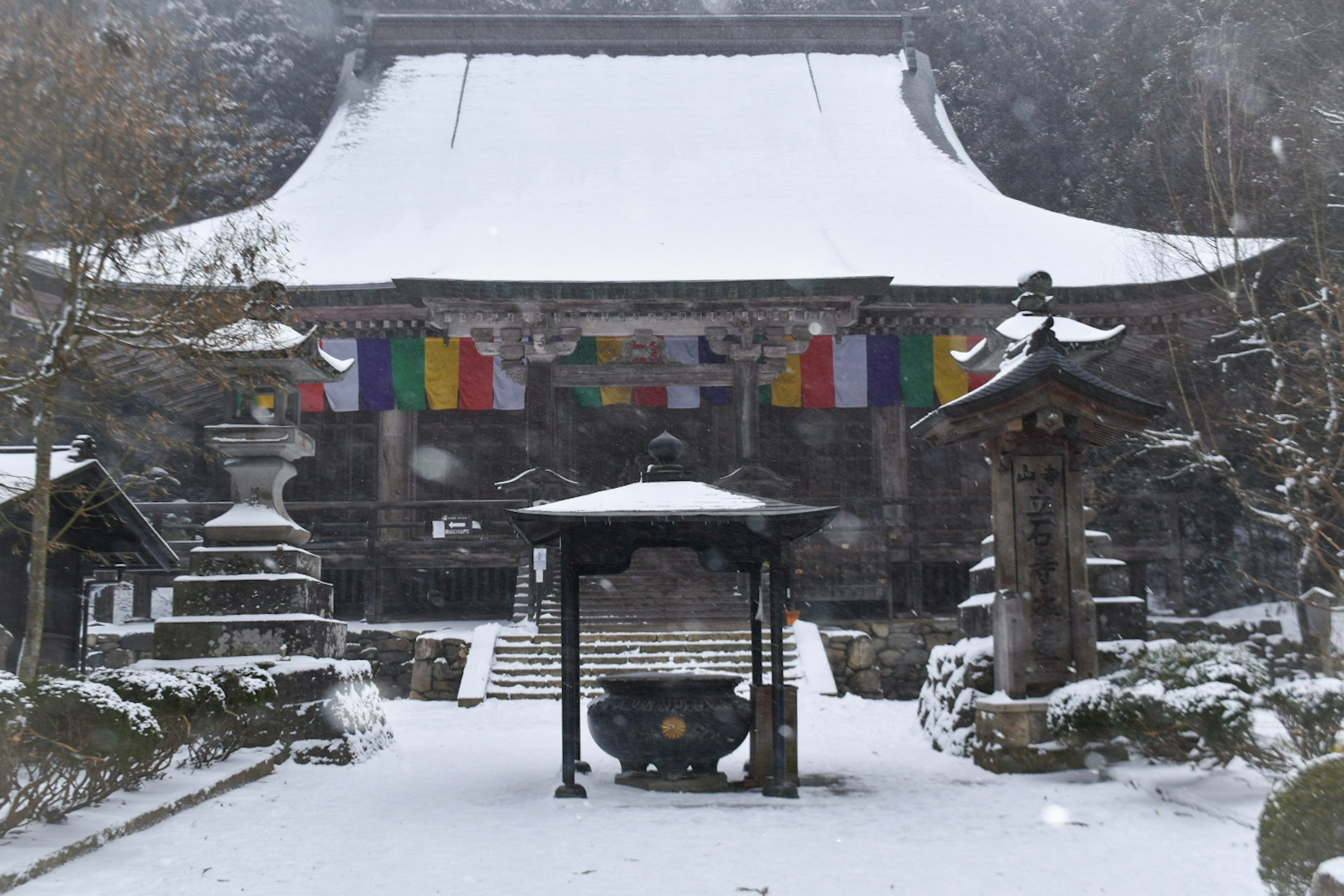 雪に覆われた寺院の前景にカラフルな旗が飾られている