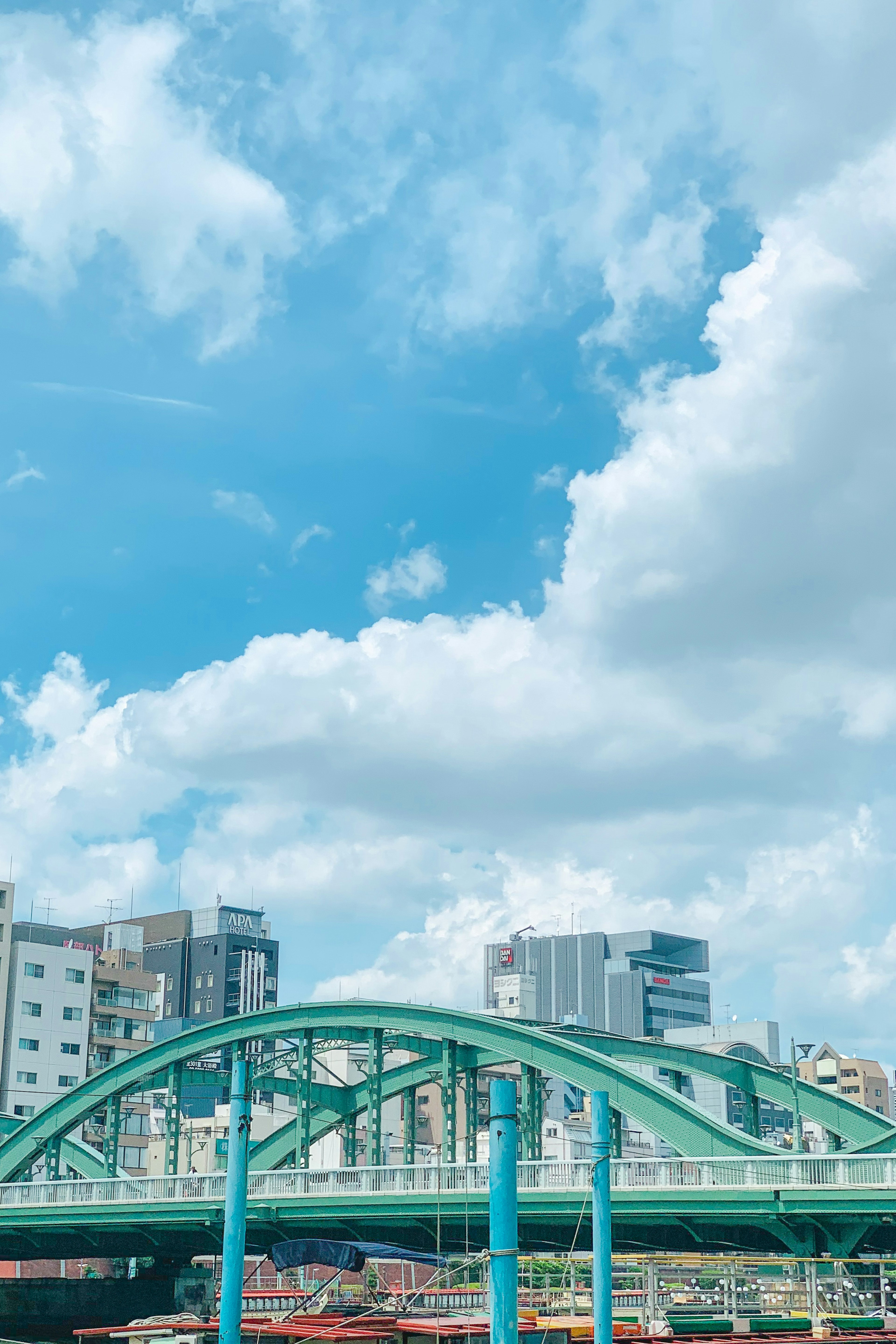 Pont vert sous un ciel bleu avec des nuages blancs et des bâtiments