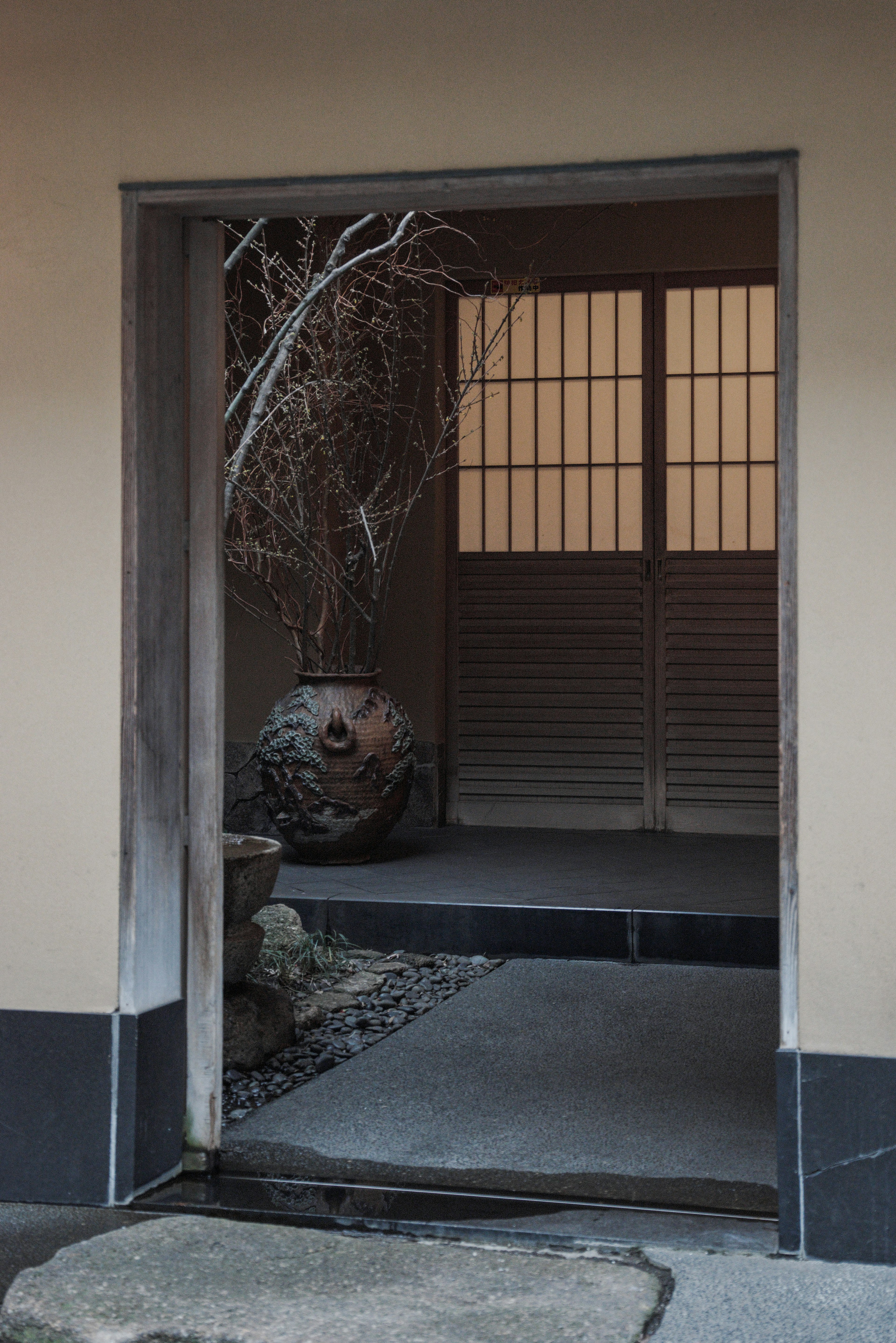 Simple Japanese entrance architecture with shoji doors stone flooring and natural elements decoration