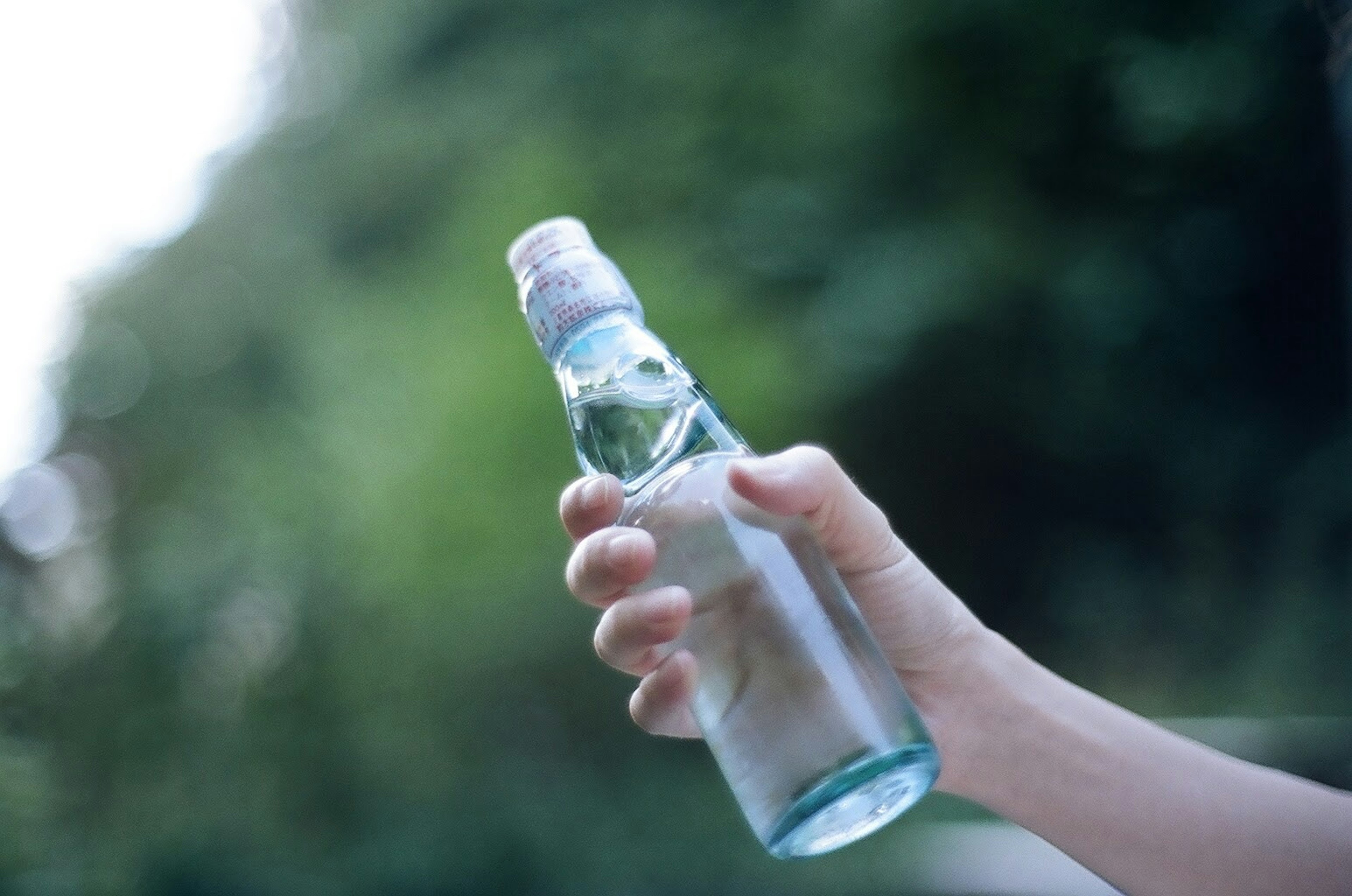 Close-up of a hand holding a water bottle with a green background