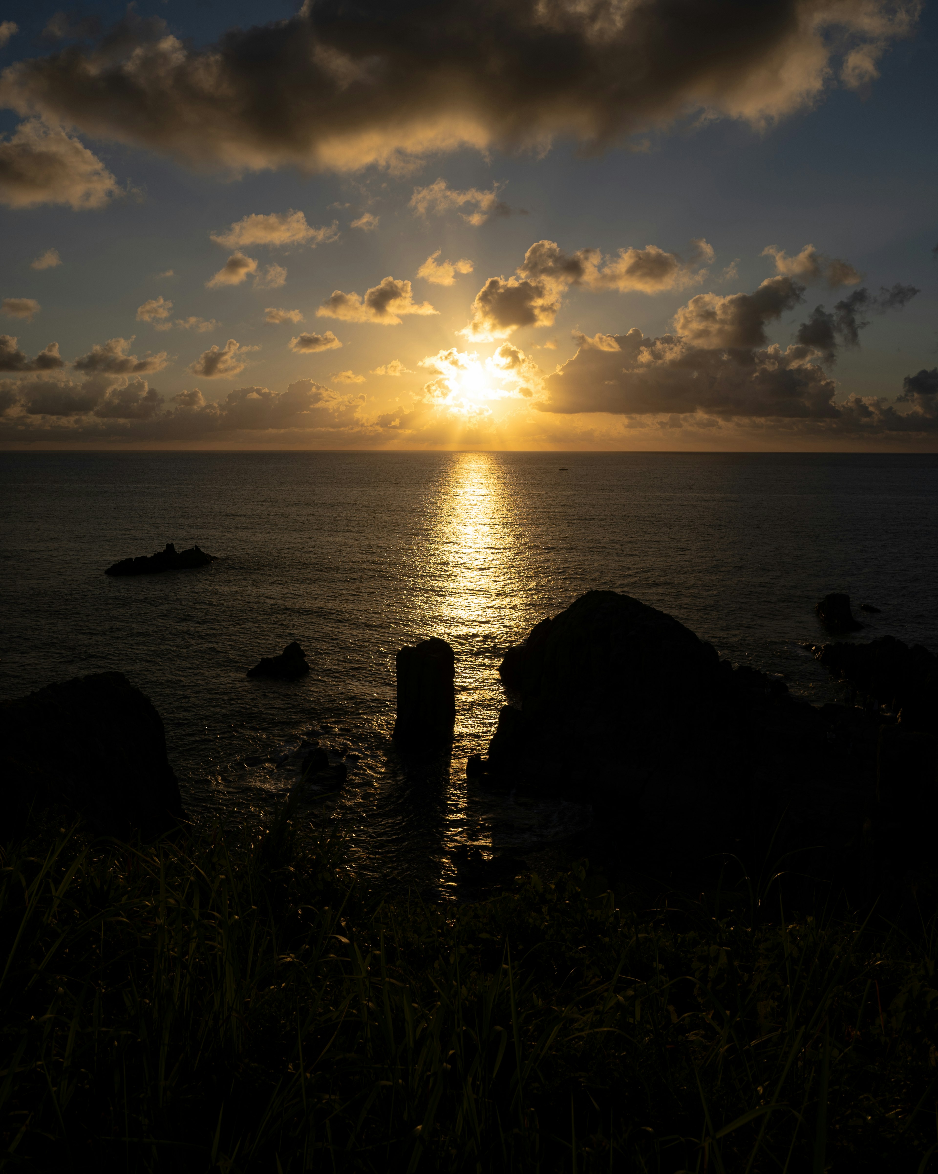 Beautiful landscape of sunset over the ocean with silhouettes of rocks