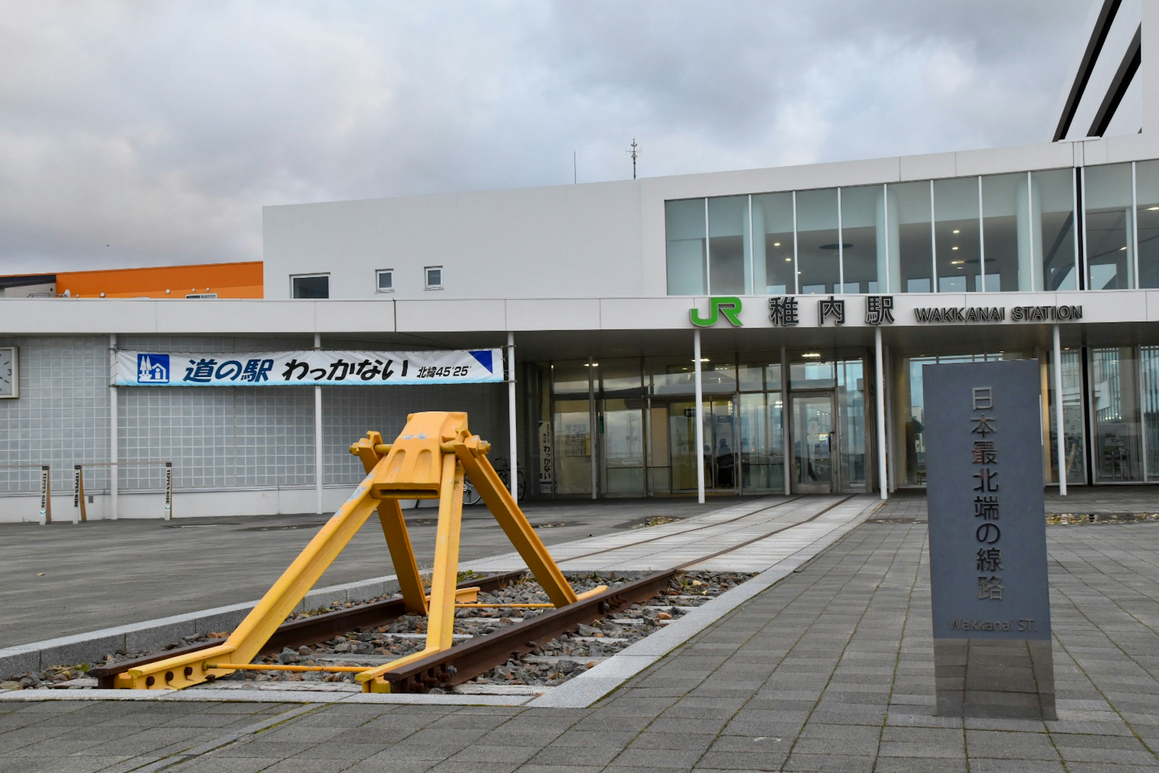 Estremità ferroviaria gialla e esterno della stazione