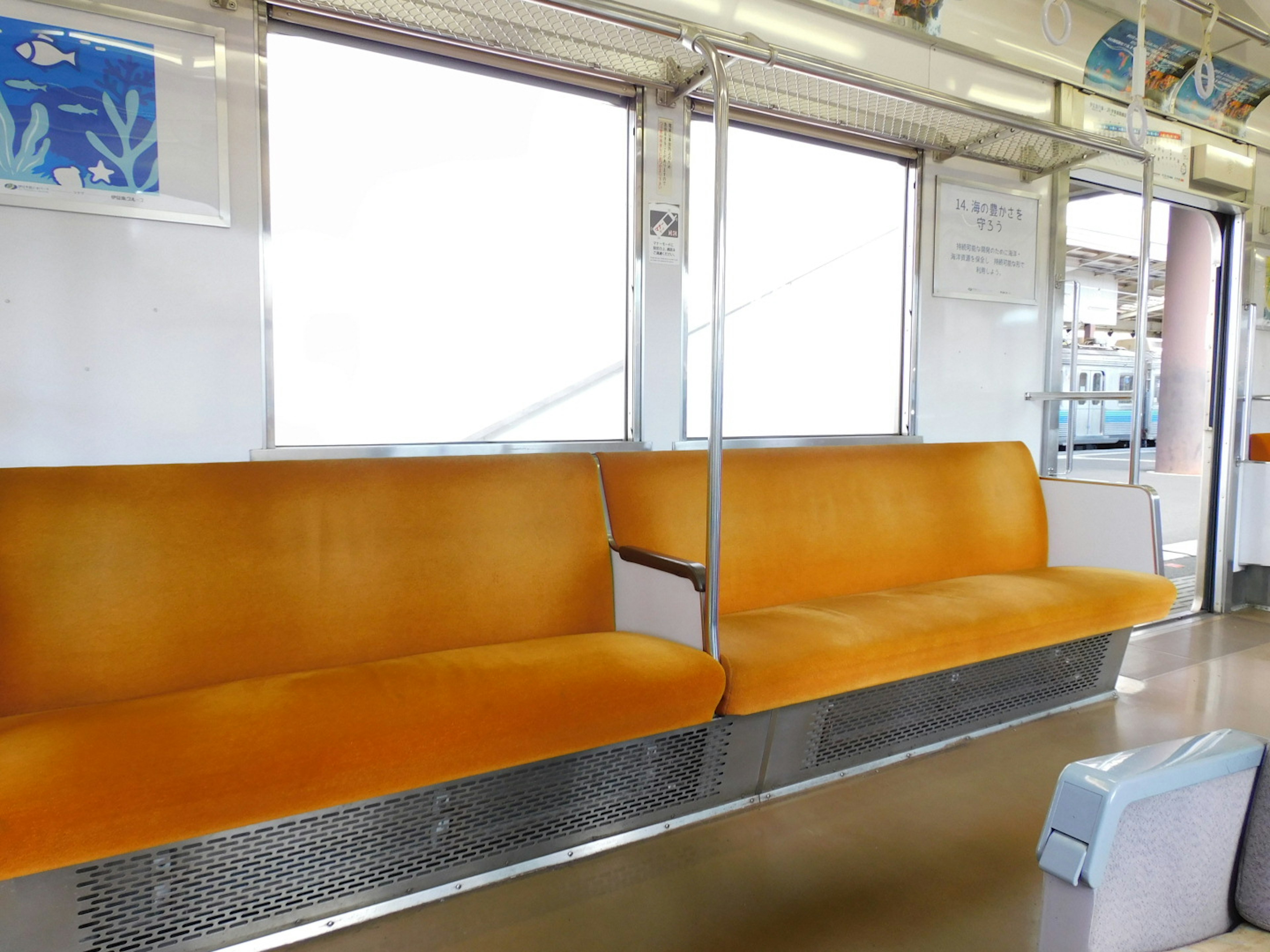 Interior of a train with bright orange seats and large windows