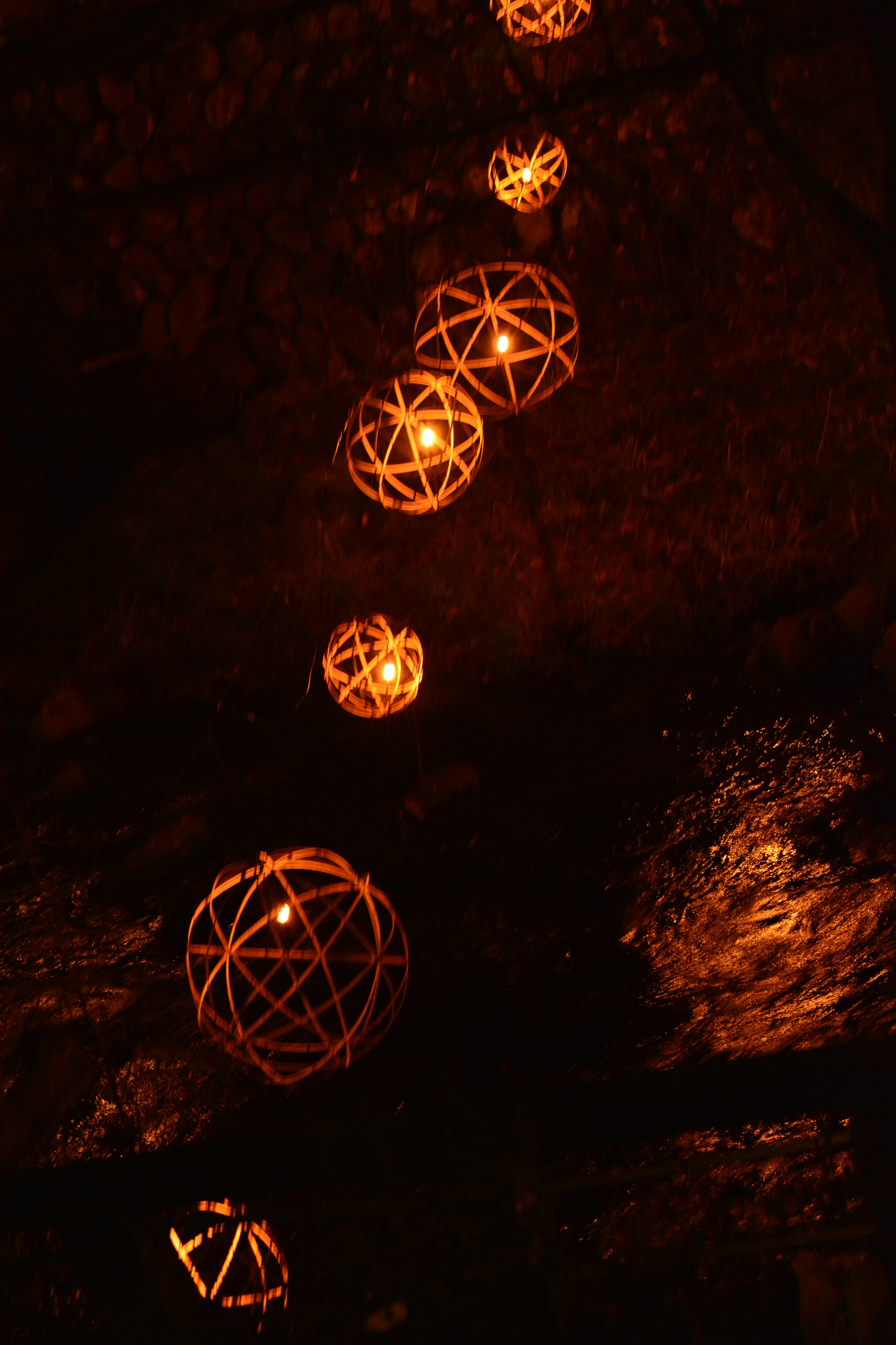 Orange lanterns hanging against a dark background with spherical designs glowing