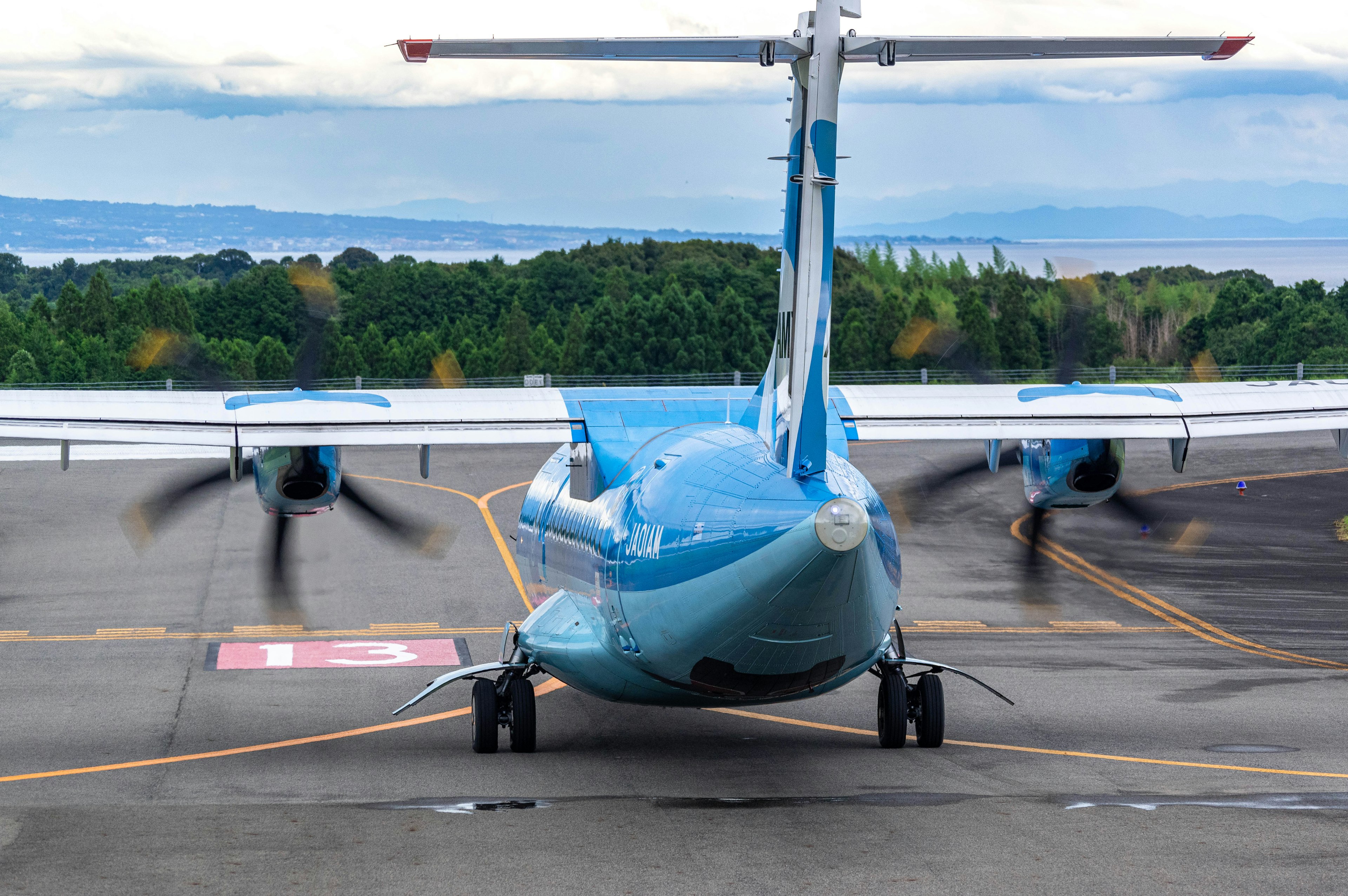 Pesawat propeller biru diparkir di landasan