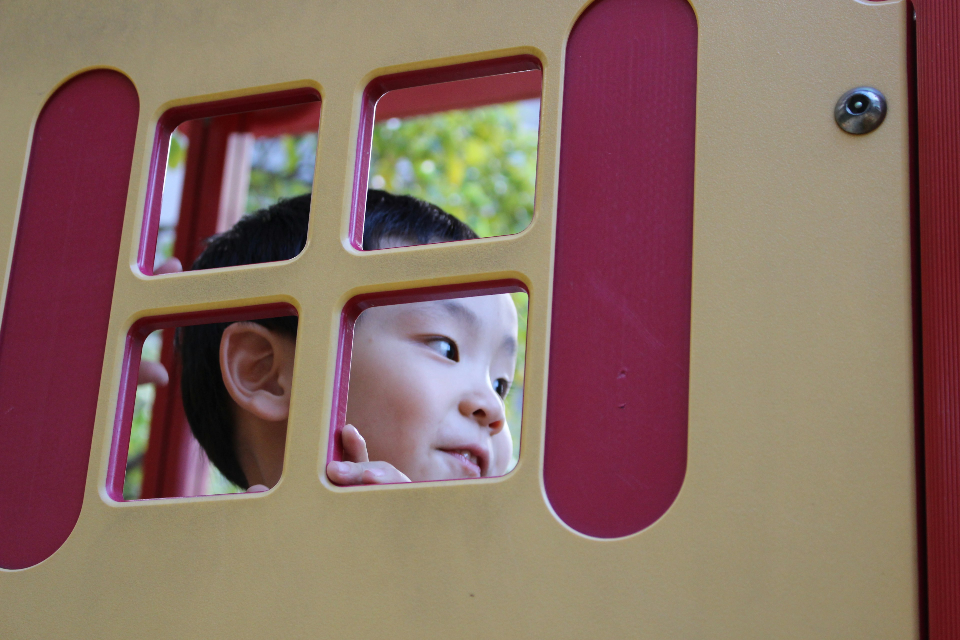 Kind schaut durch ein Fenster einer Spielstruktur