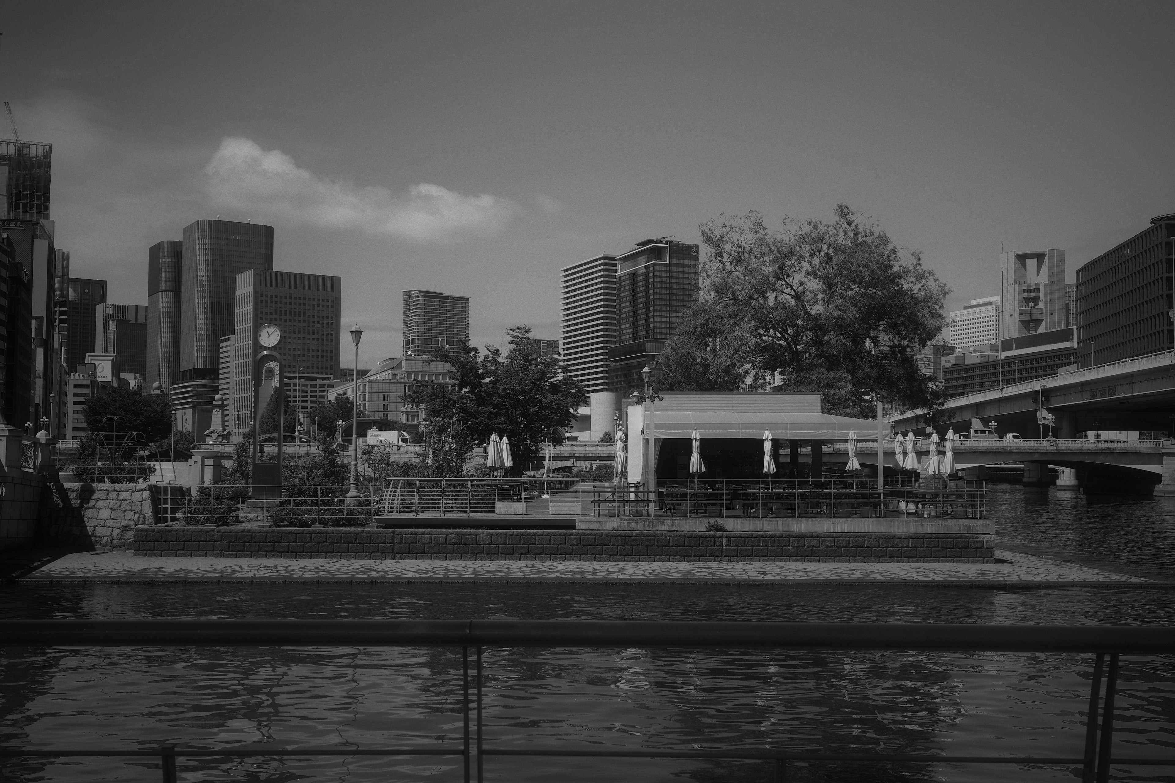 Foto en blanco y negro que presenta un paisaje urbano y un café junto al río