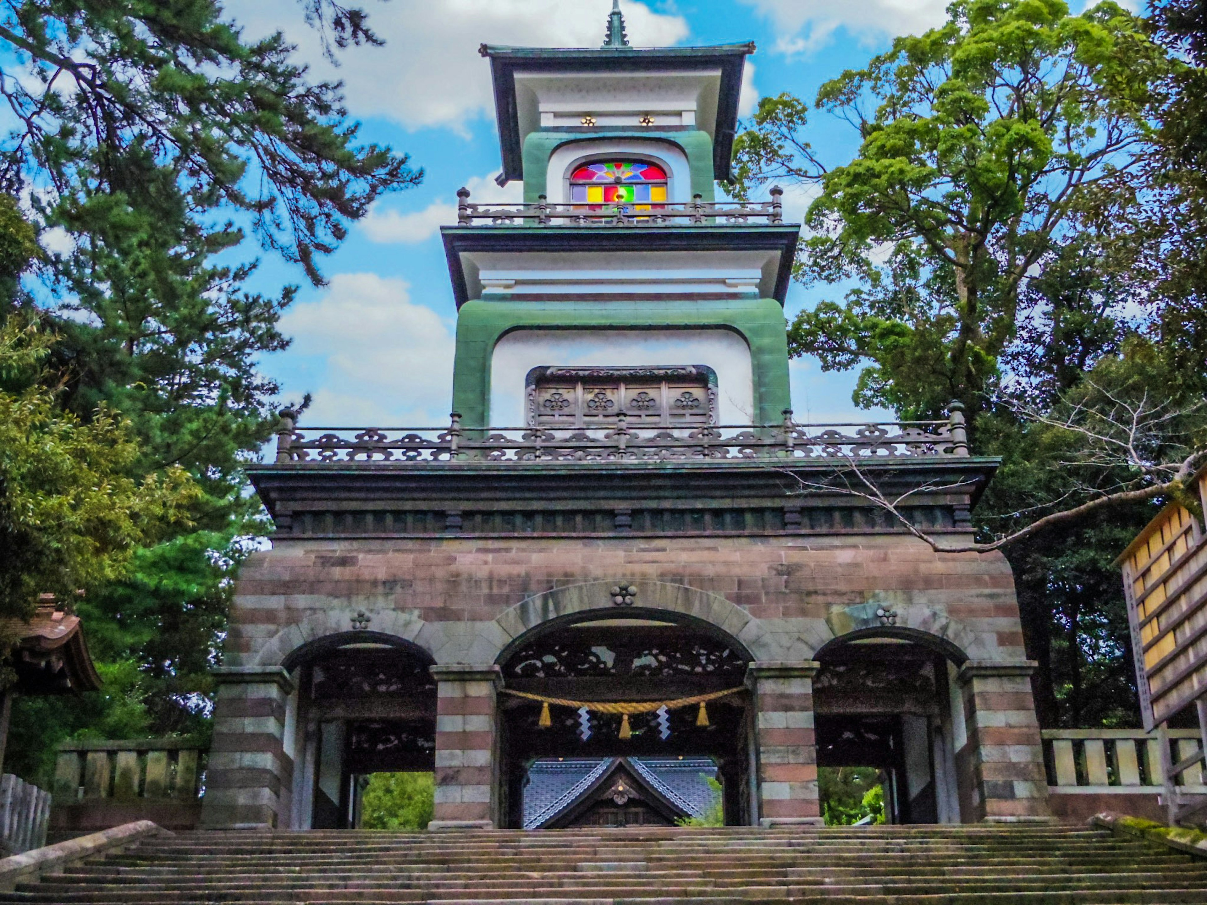 緑色の屋根を持つ塔のある神社の建物 階段と木々に囲まれた景色