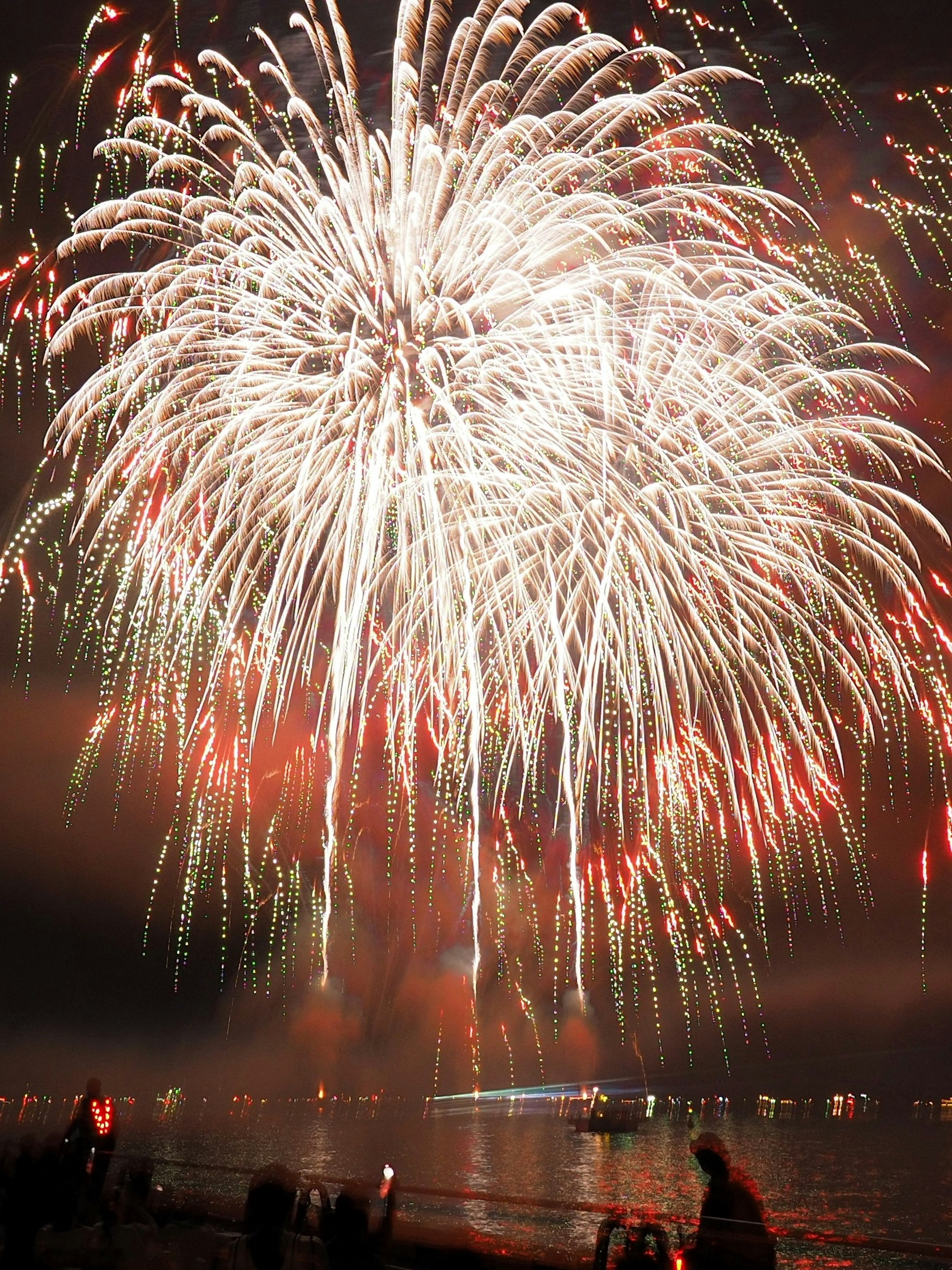 夜空に広がる華やかな花火のショーと観客のシルエット