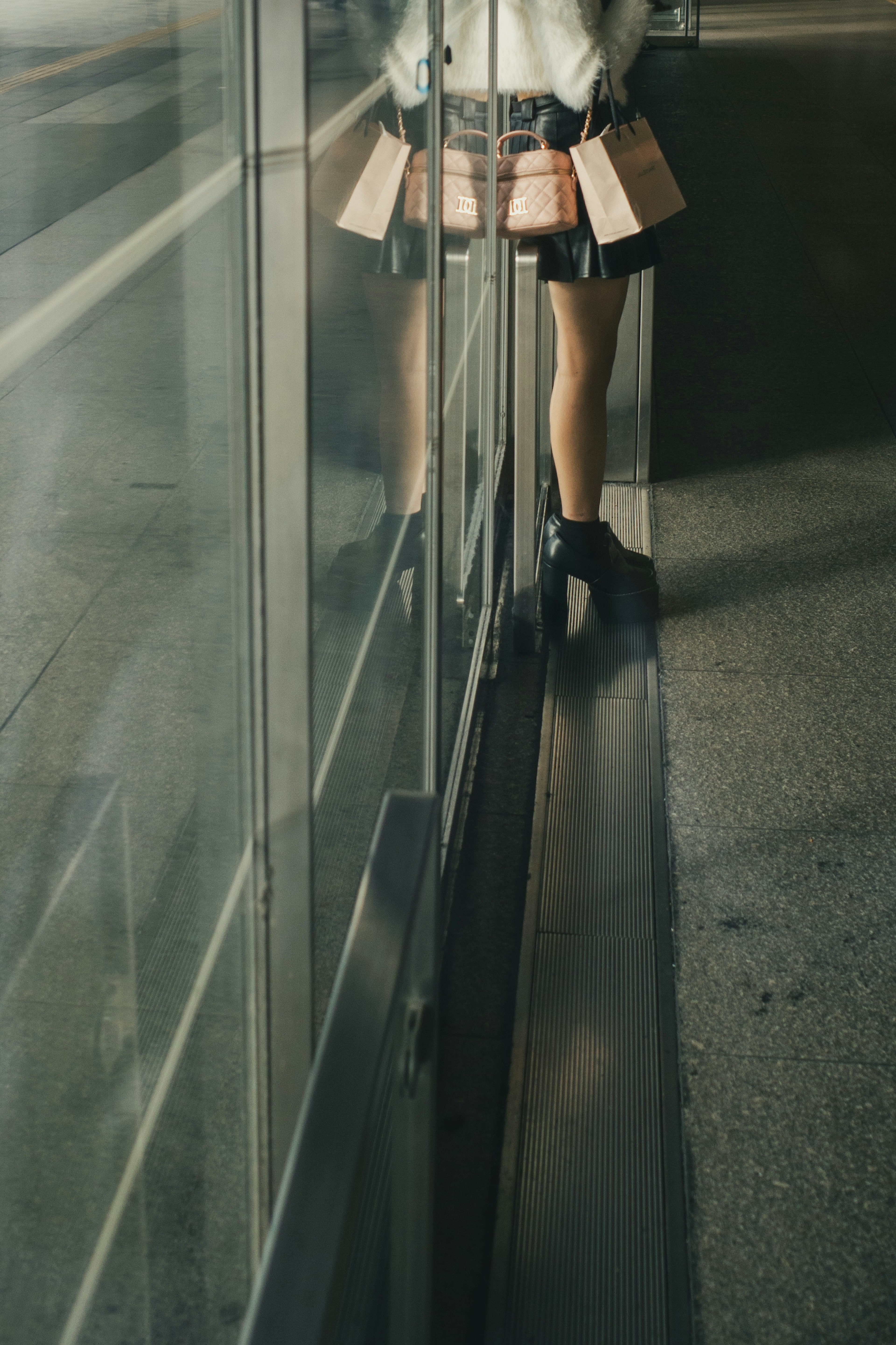 A person's legs and part of a skirt in front of a glass wall