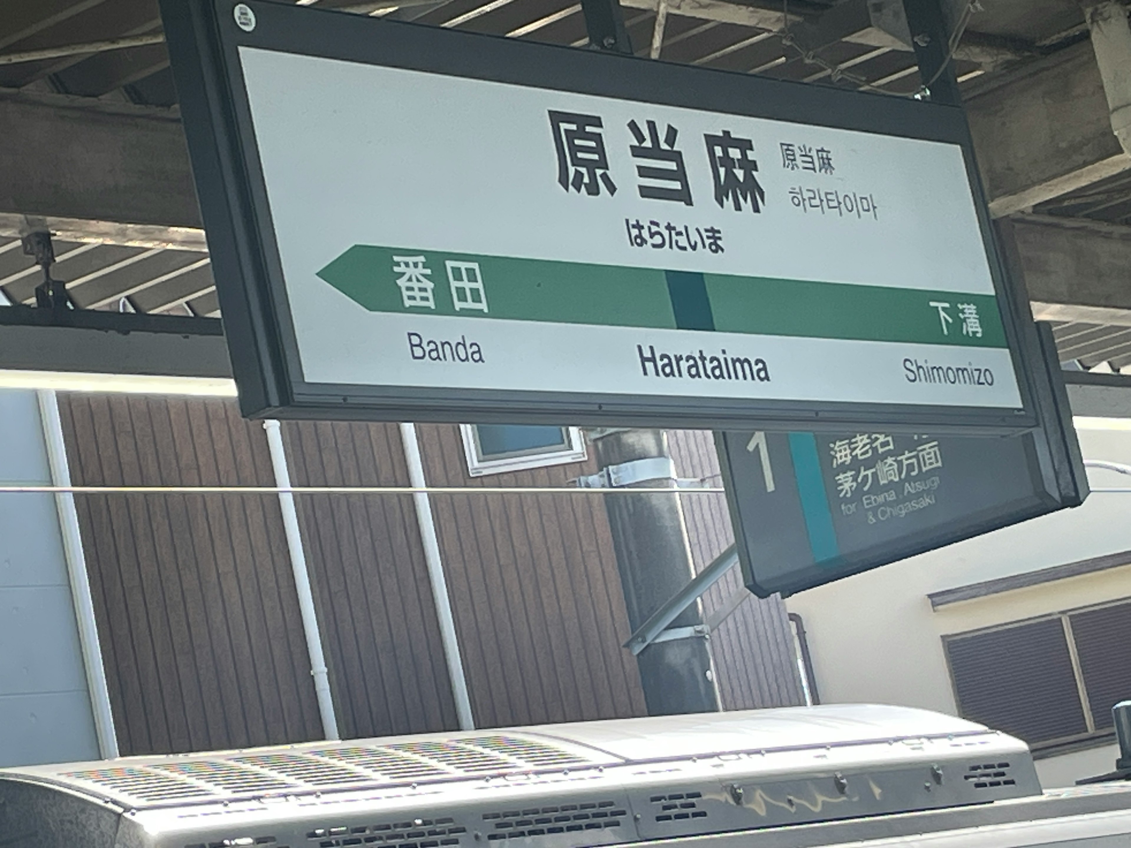 Sign for Haratama Station showing directions and station name