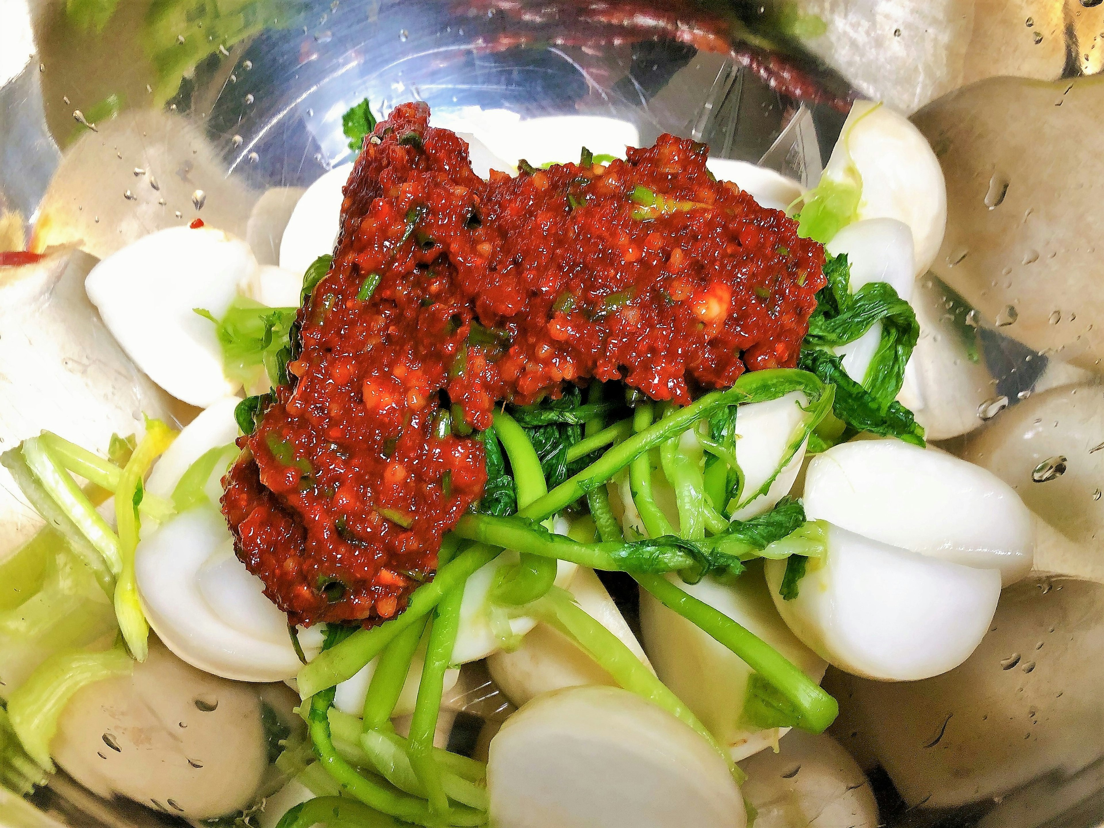 A bowl filled with white vegetables and a red condiment on top