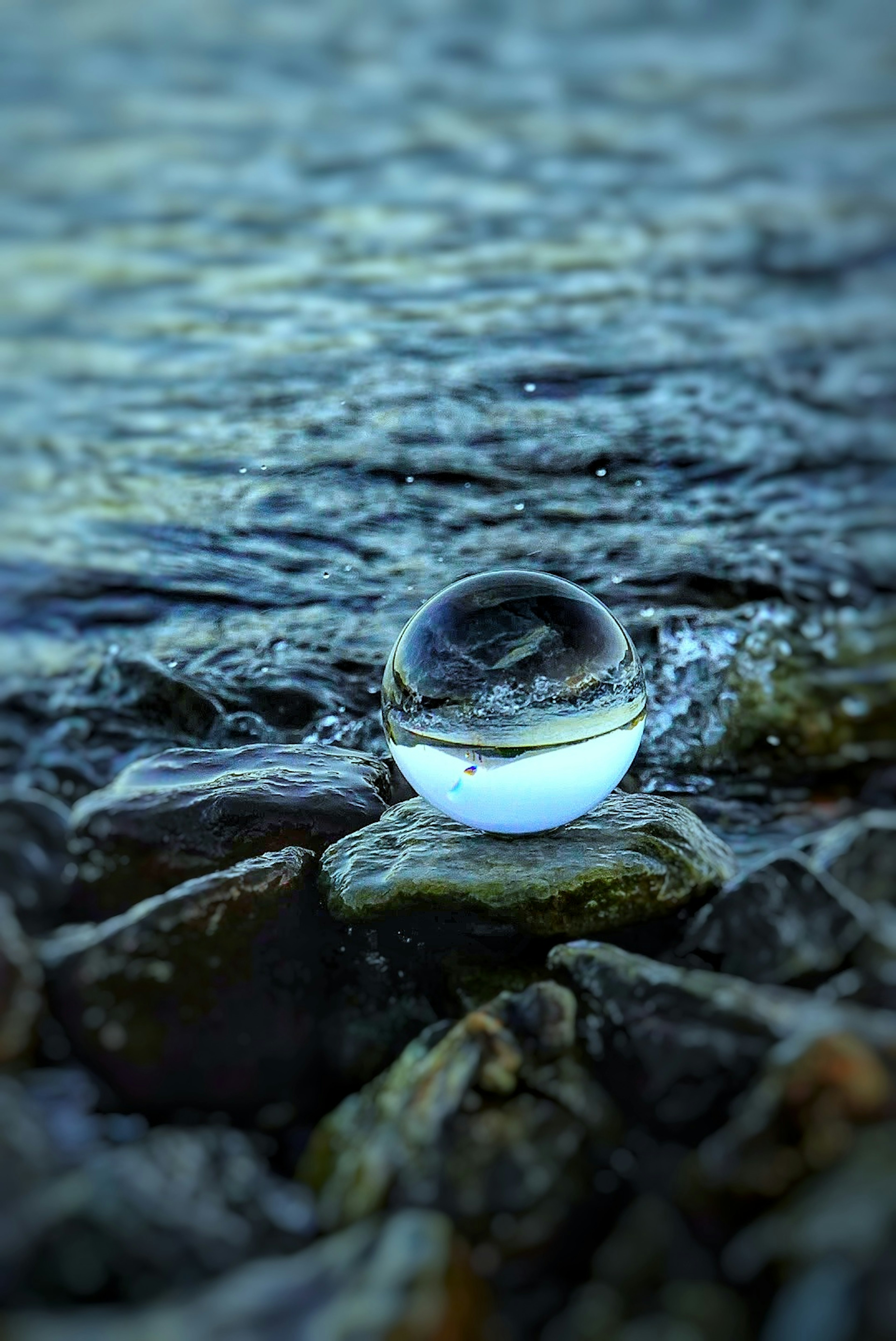 Boule en cristal reposant sur des rochers au bord de l'eau