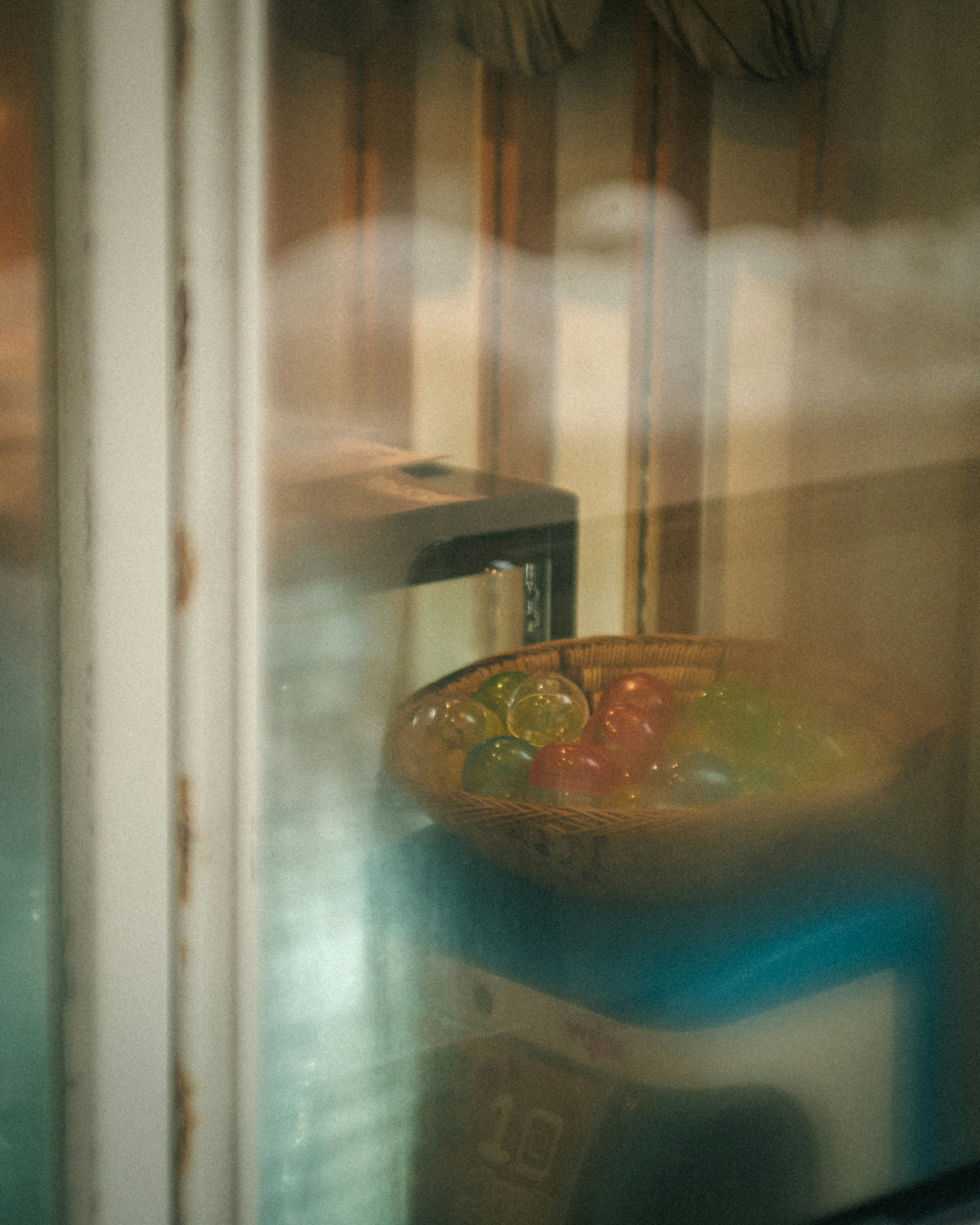 Colorful jelly bowl seen through foggy glass with vintage furniture