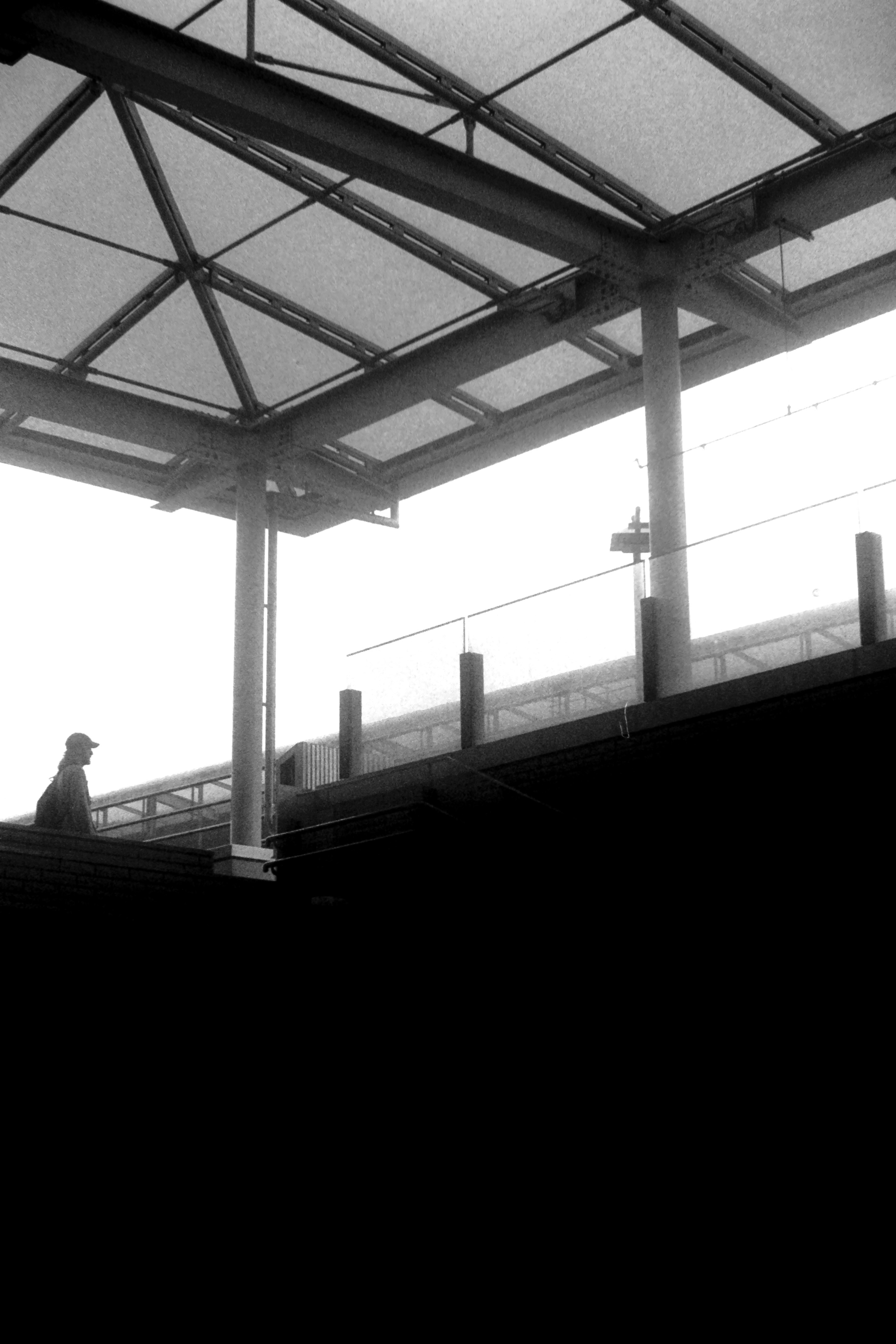 Silhouette of a person standing on a train platform with a transparent roof