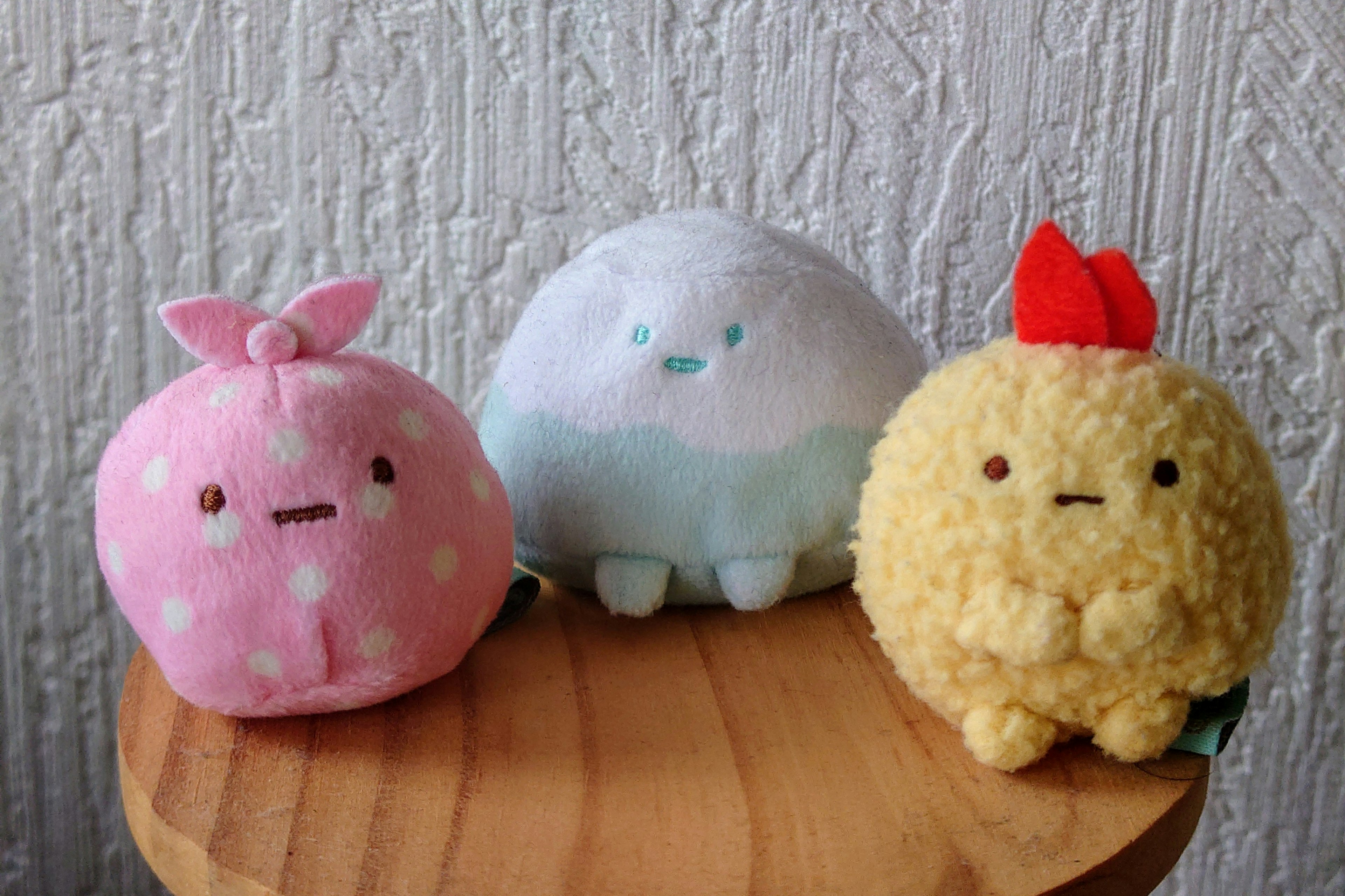 Three cute plush toys sitting on a wooden table