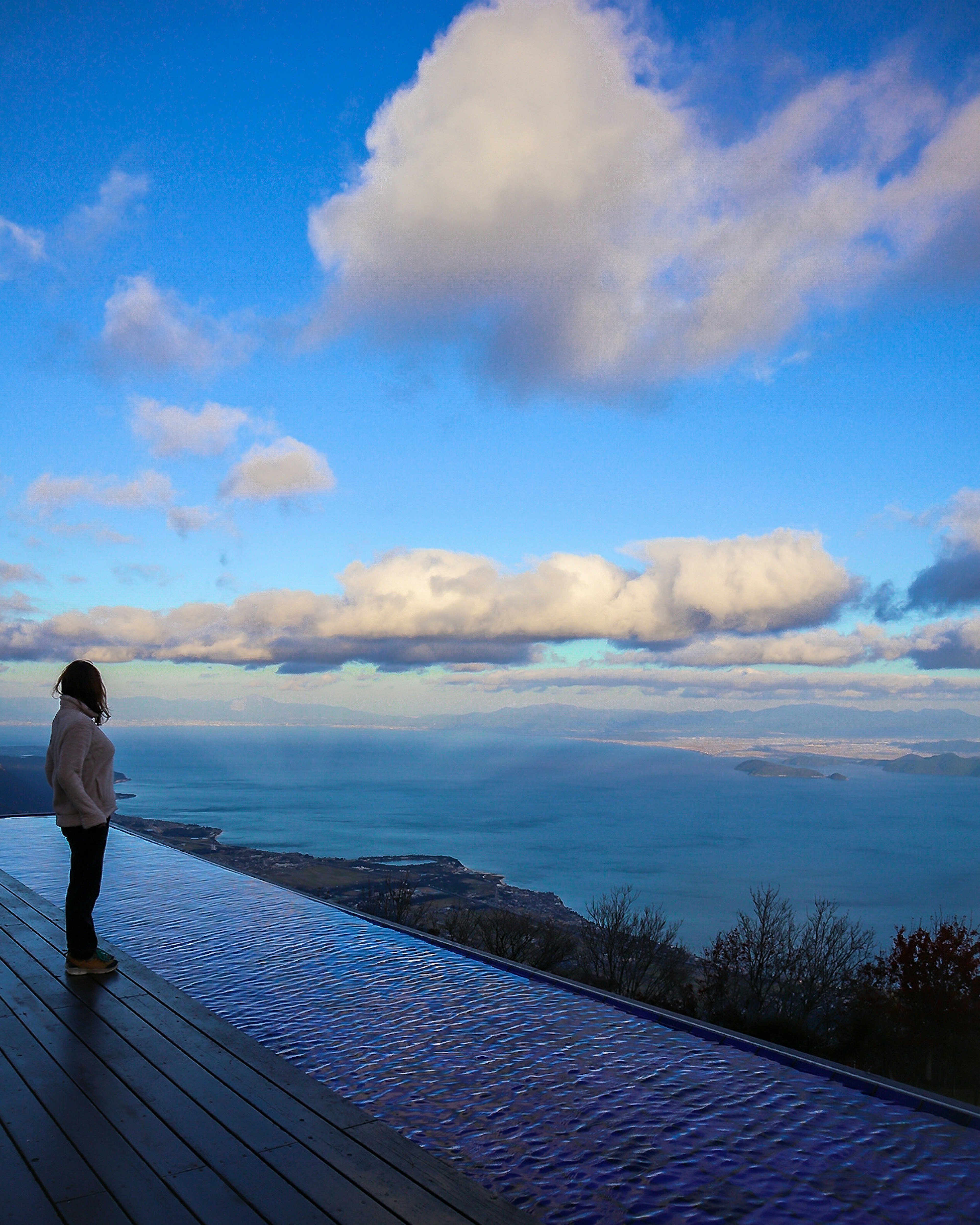 Silhouette di una donna che guarda il mare contro uno sfondo di cielo blu e nuvole