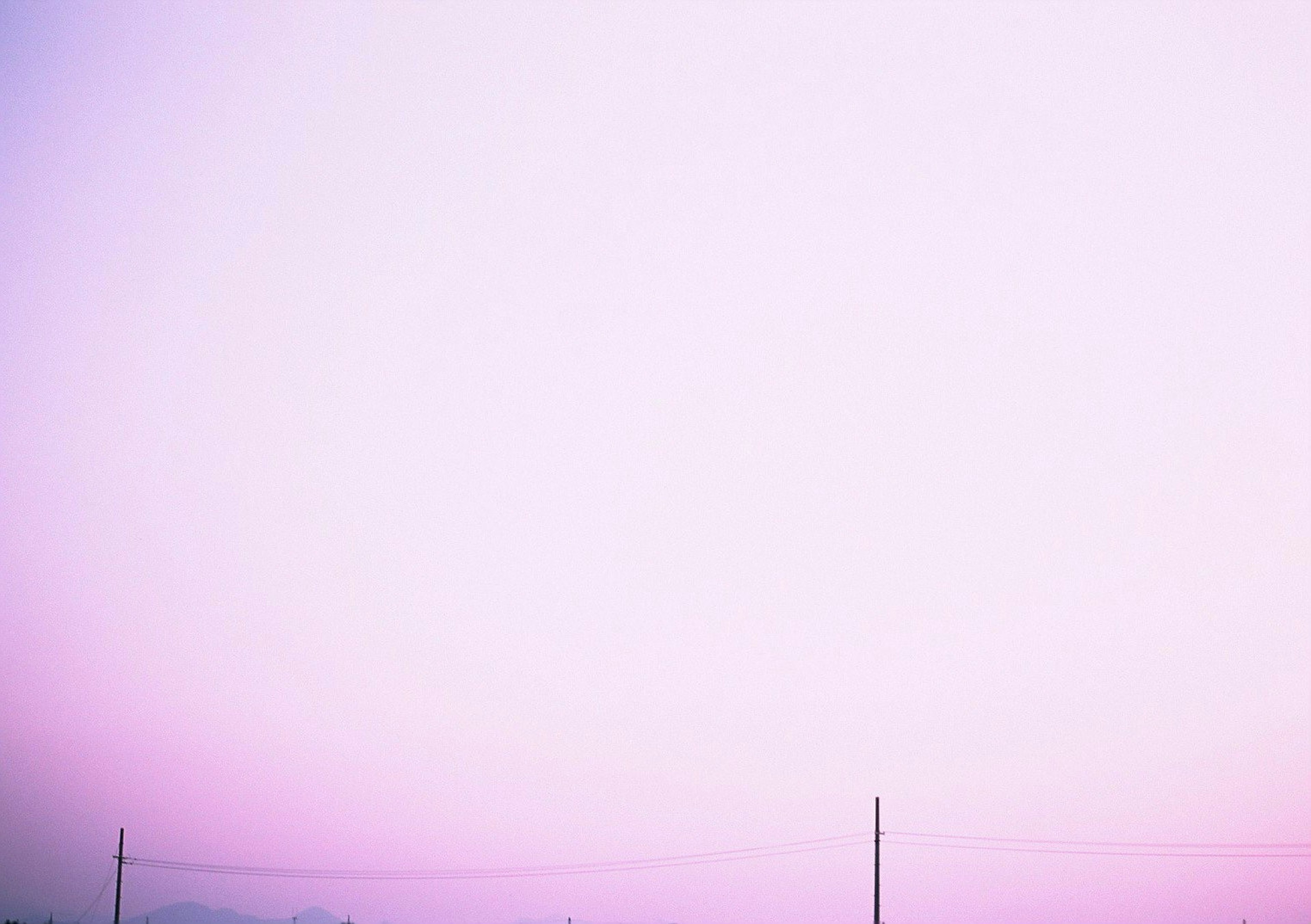 Eine Landschaft mit einem blassen lila Himmel und Silhouetten von Strommasten