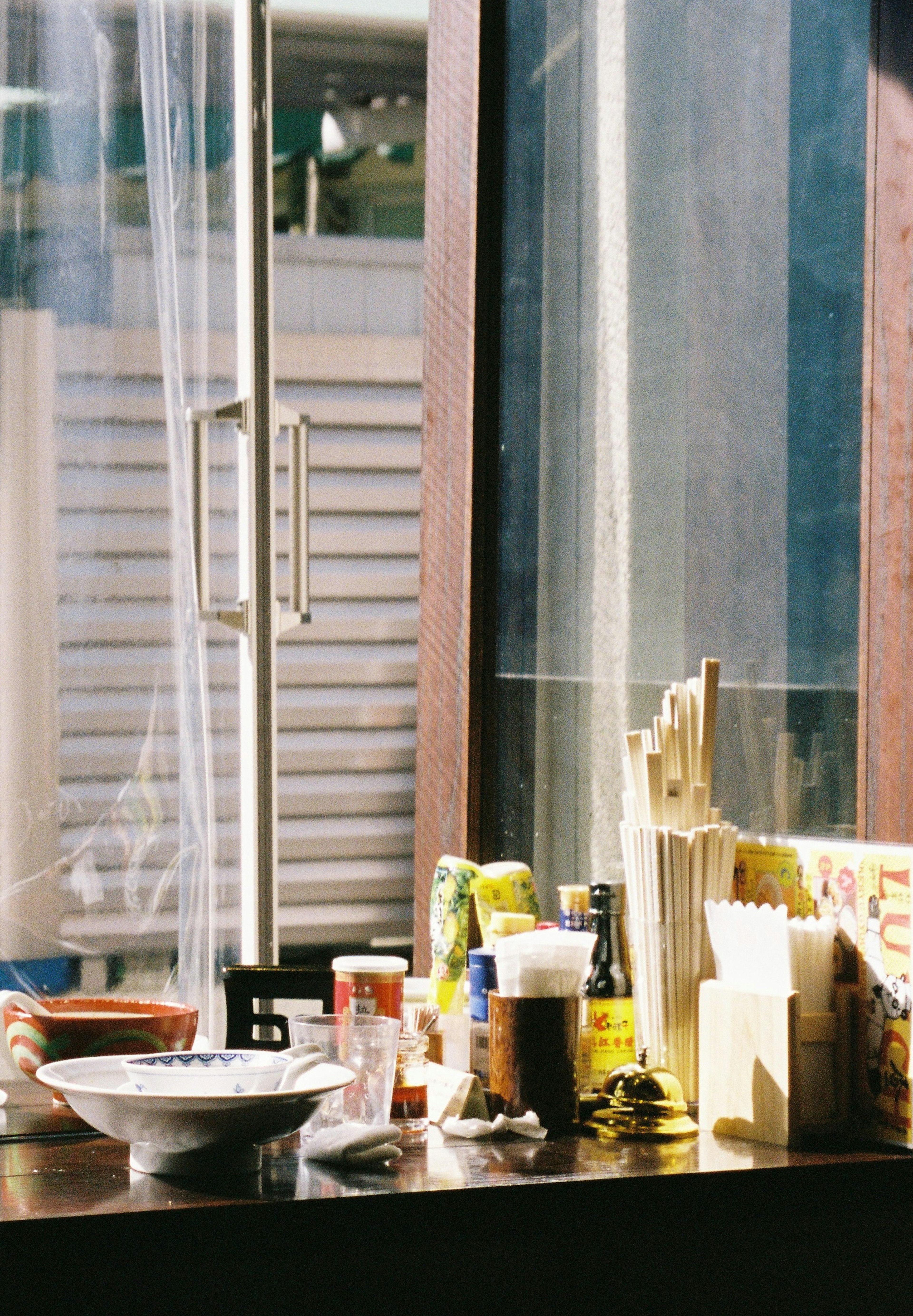 A variety of food items and condiment bottles on a table by the window