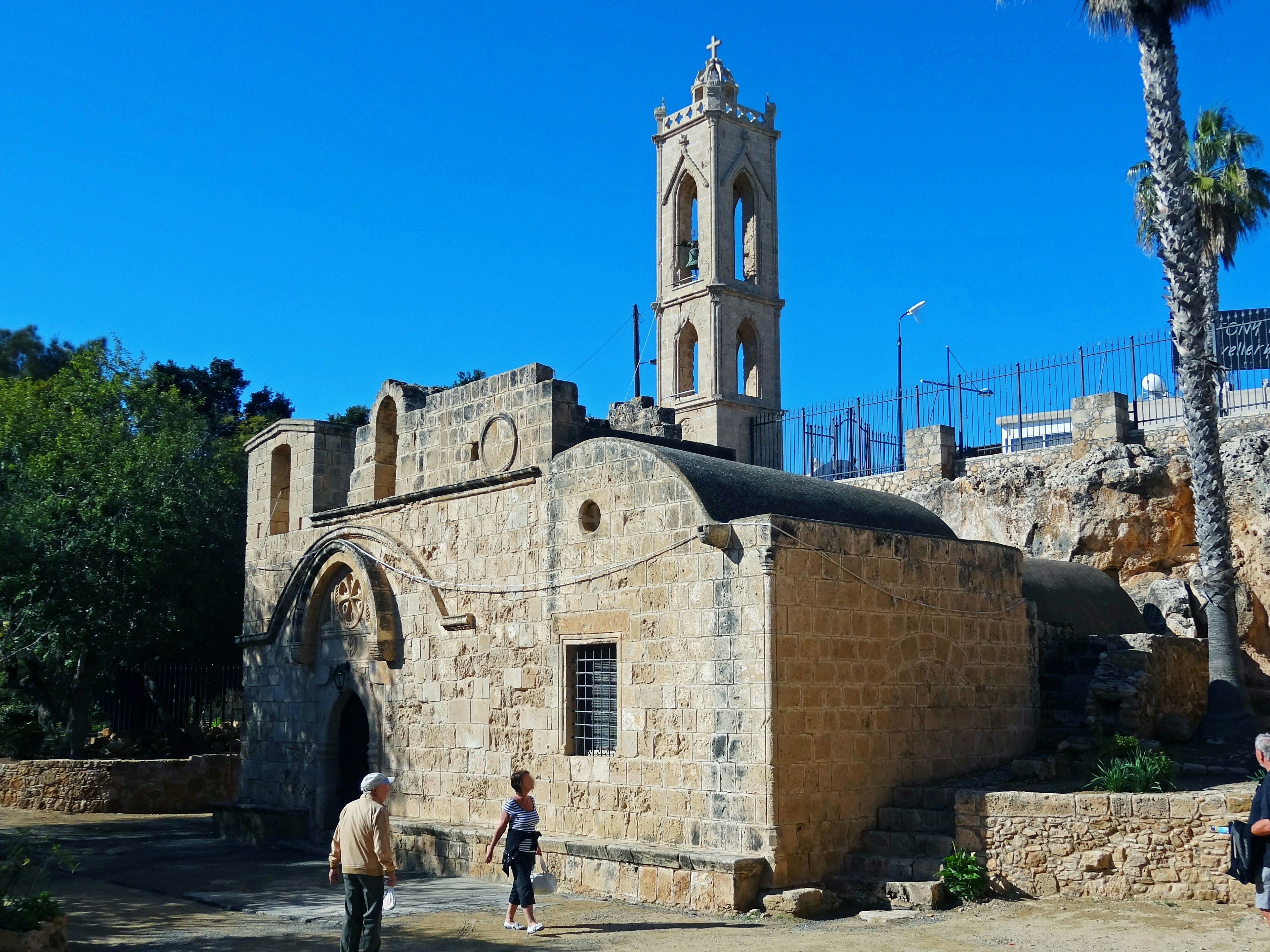 Edificio storico in pietra con una torre alta sotto un cielo blu chiaro