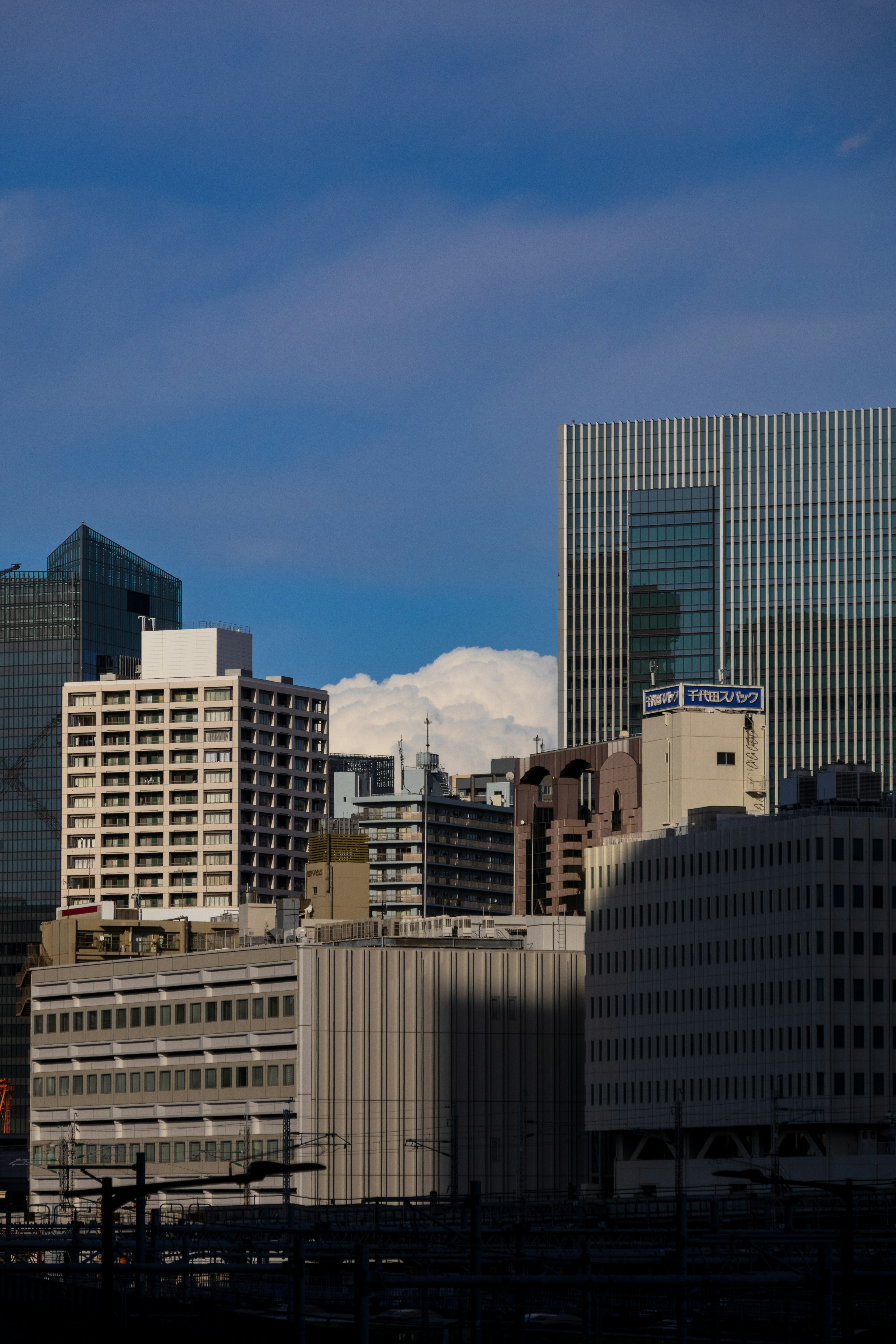 Paisaje urbano con rascacielos y nubes blancas contra un cielo azul