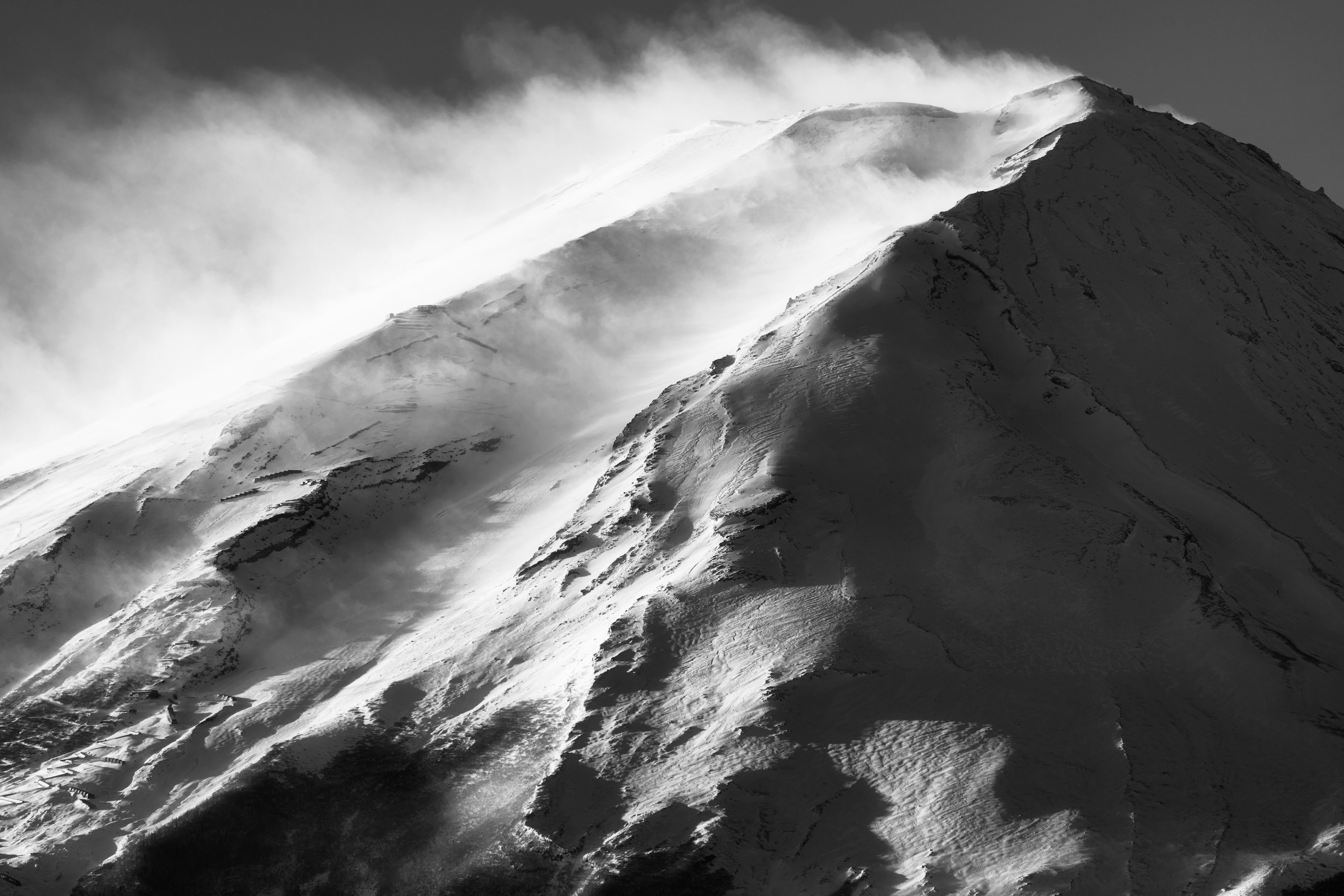 Wind and snow swirling at the mountain peak