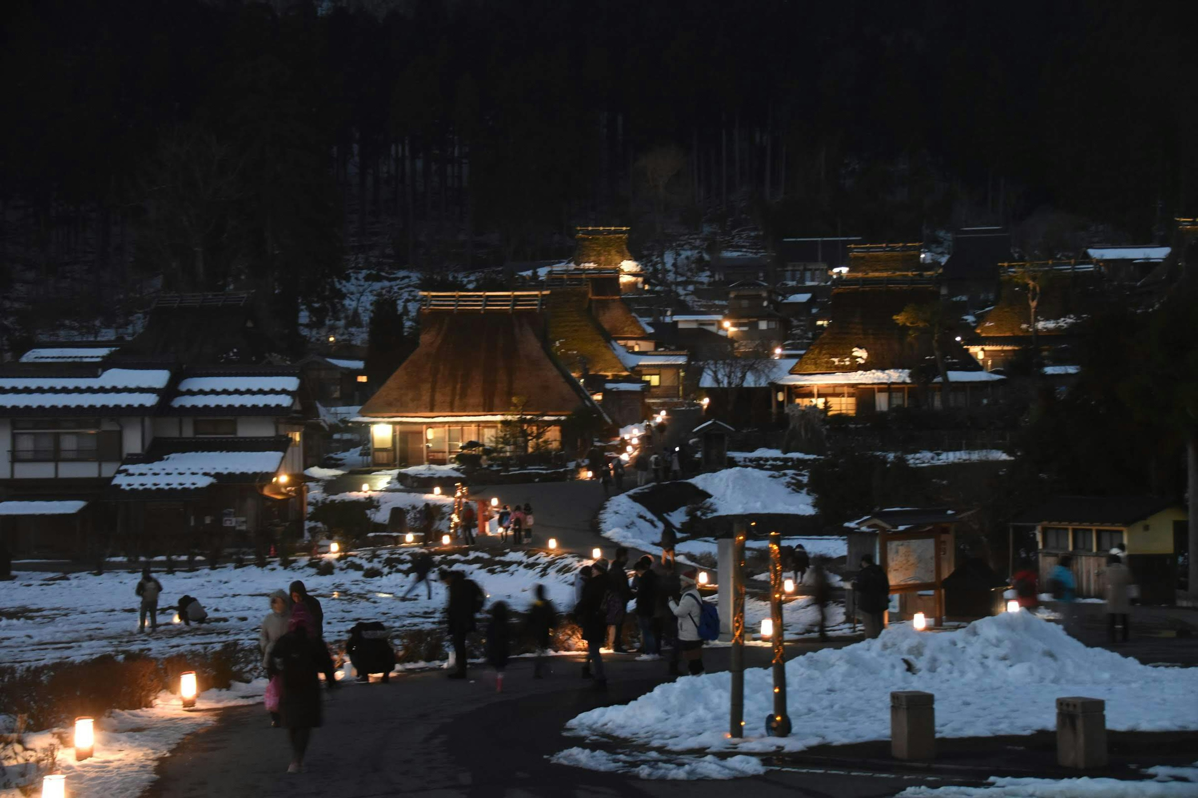 Vista nocturna de un pueblo cubierto de nieve con casas tradicionales iluminadas