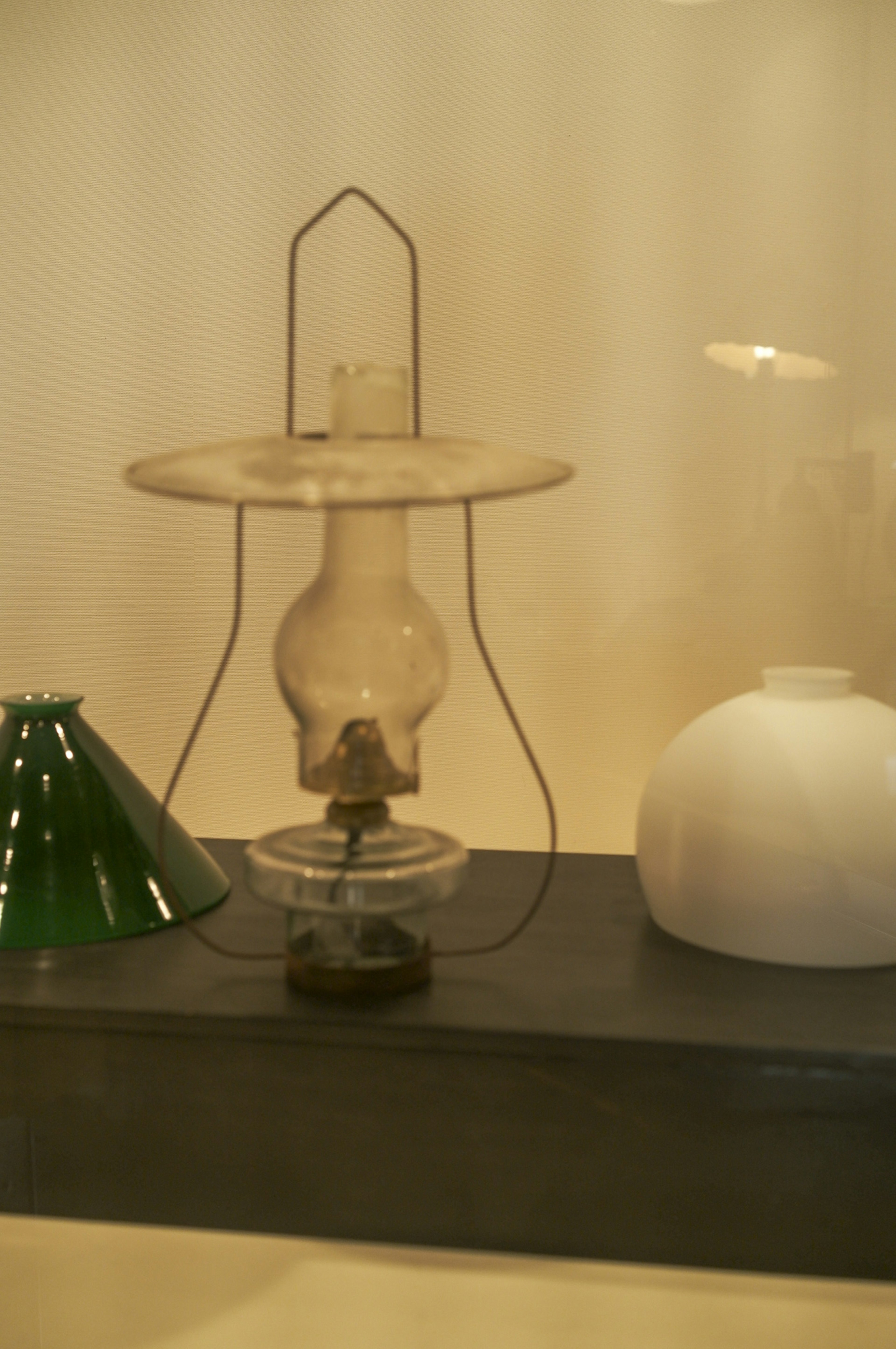 A glass lamp displayed with a green cone-shaped object and a white bowl in the background