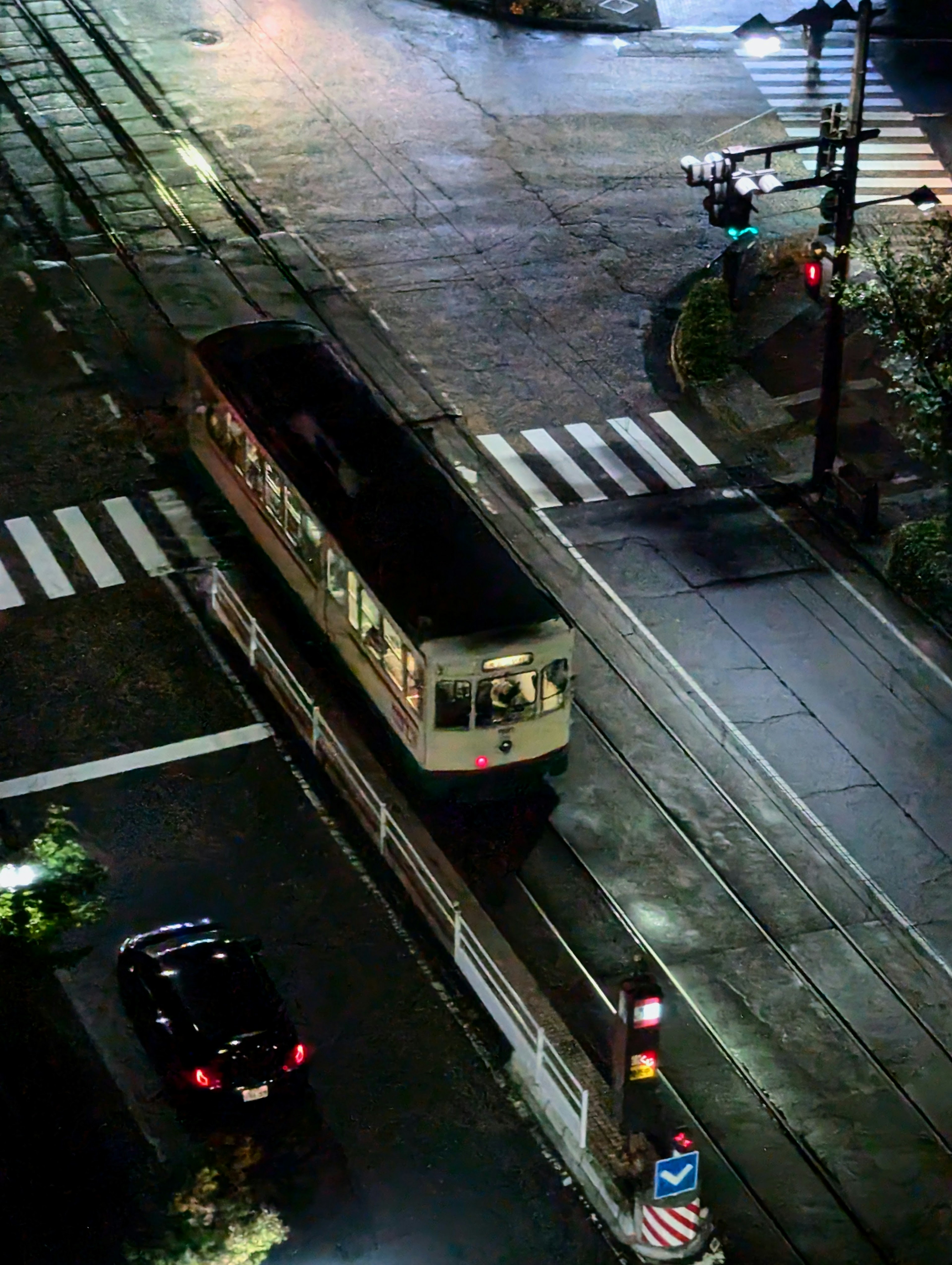 Tren ligero cruzando una intersección por la noche con semáforos