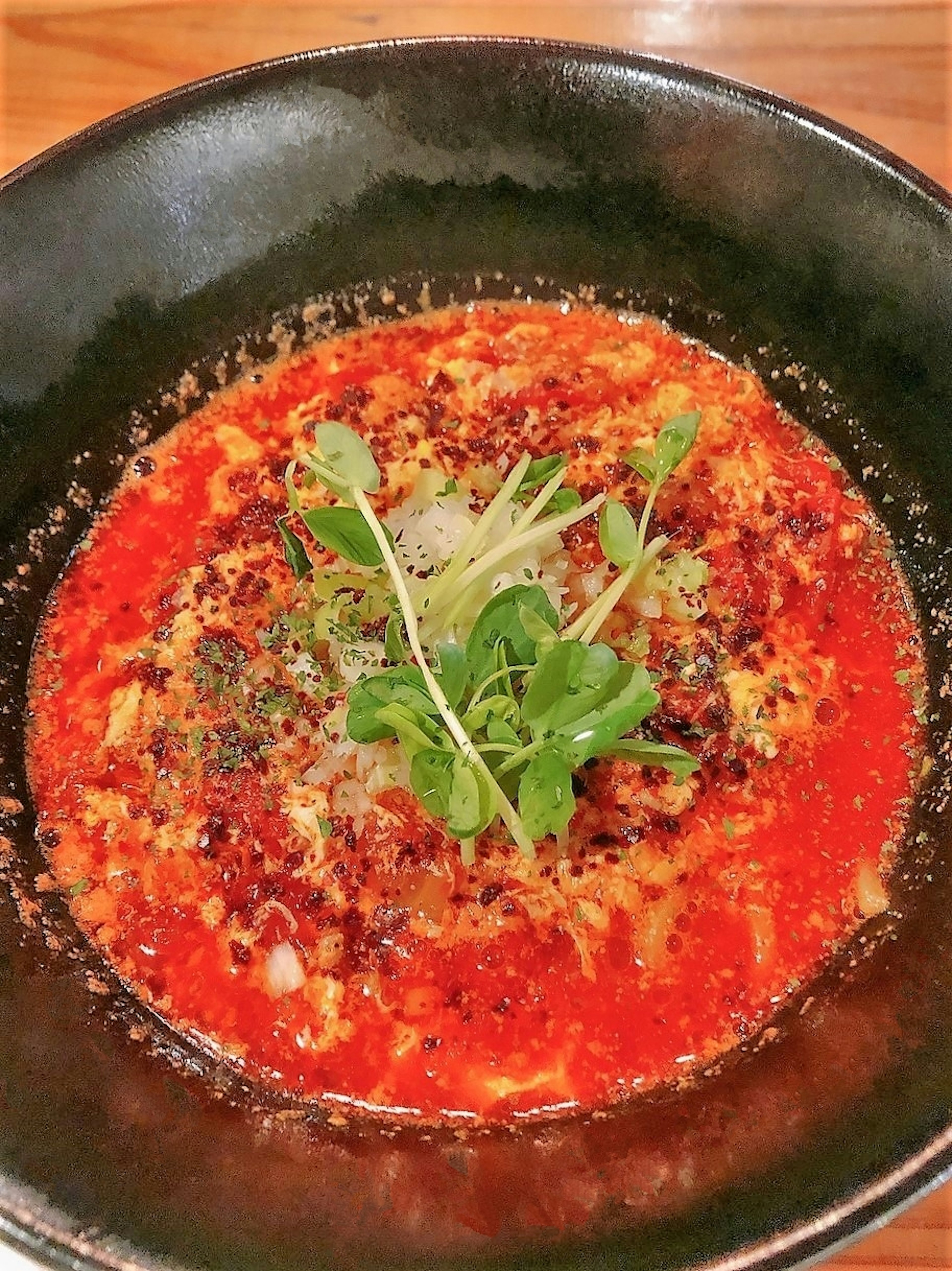 Ramen dalam sup merah pedas dengan telur dan herbal