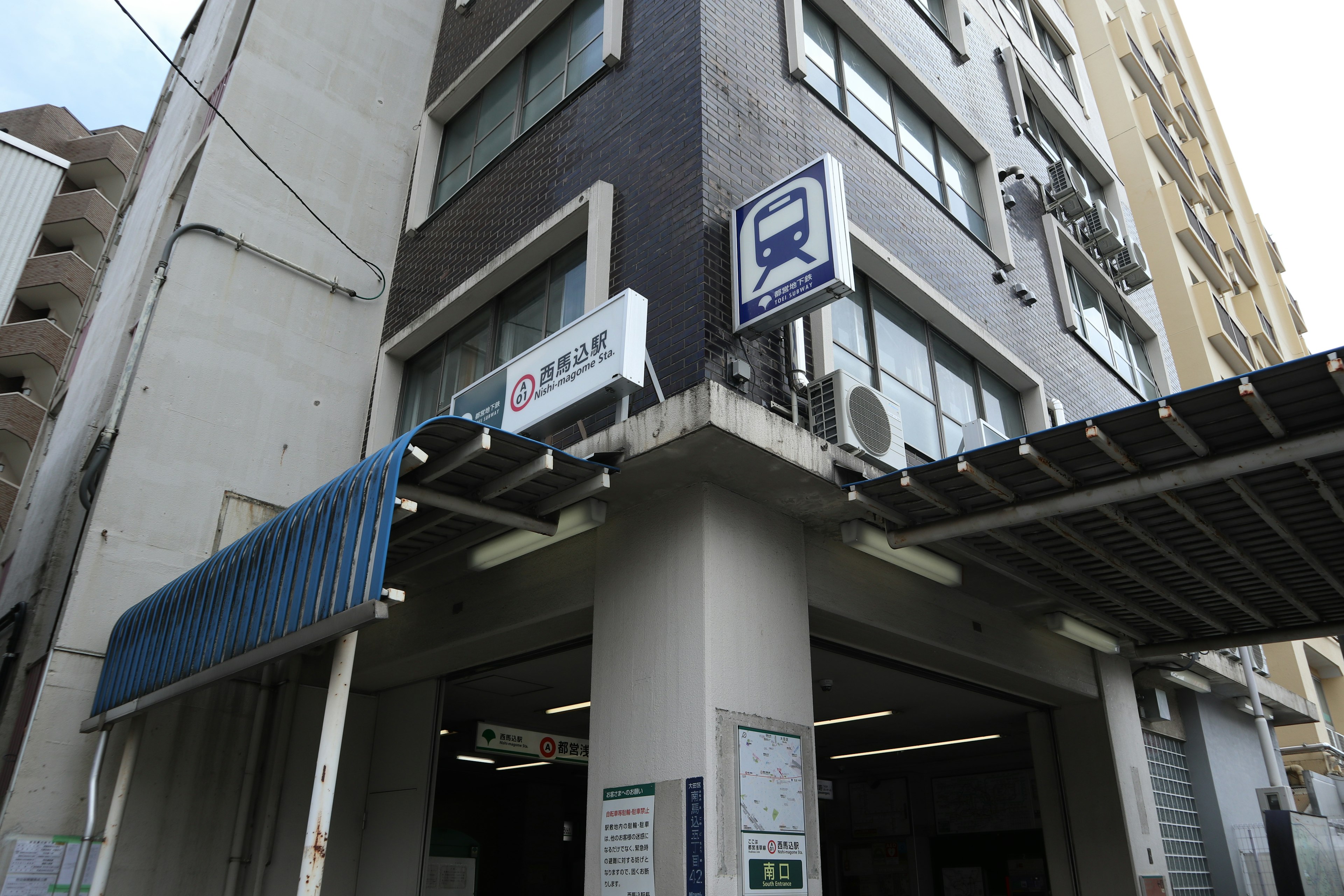 Entrance of a train station building with a black exterior and blue awning