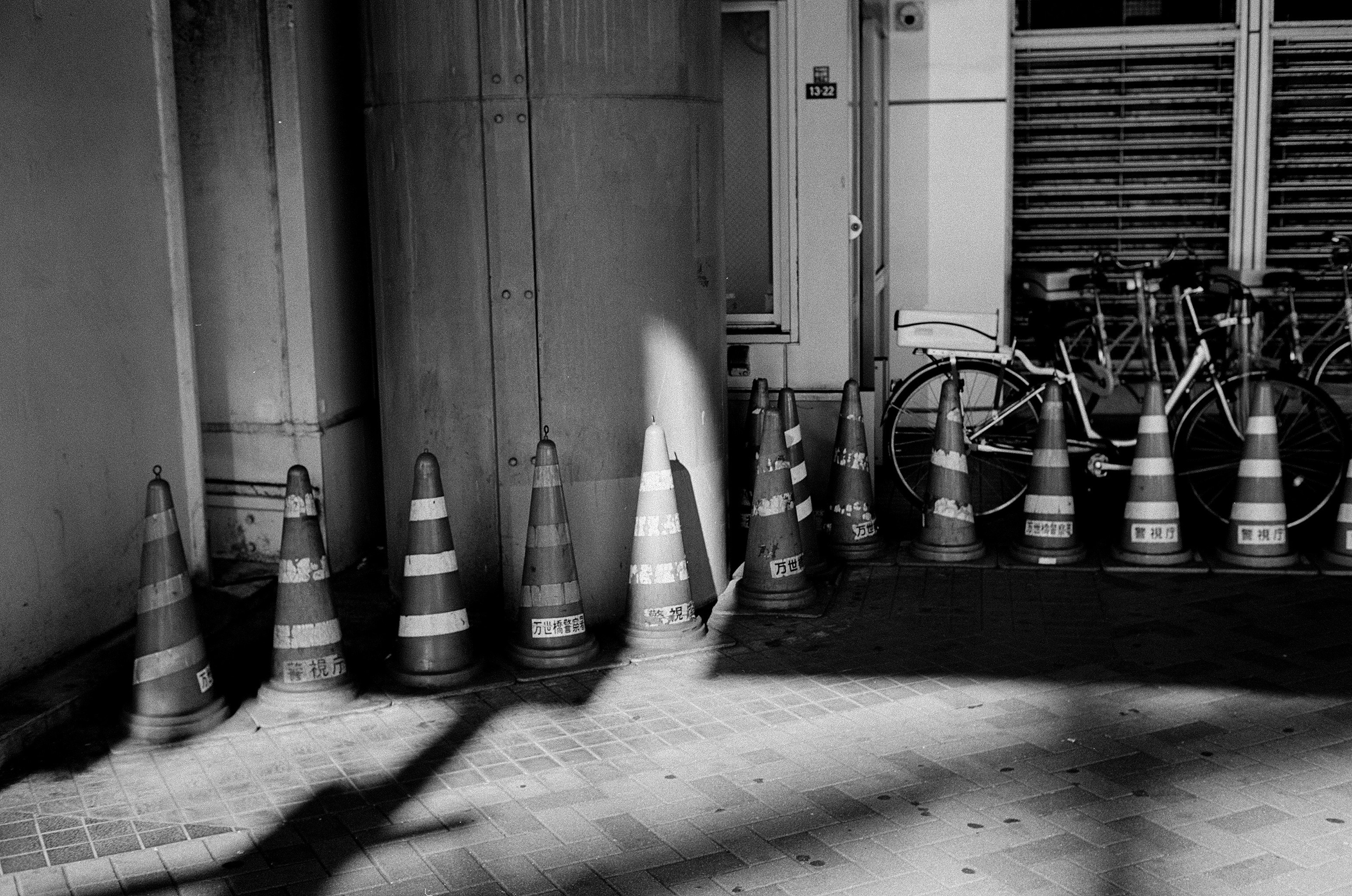 Black and white photo featuring lined traffic cones and part of a bicycle