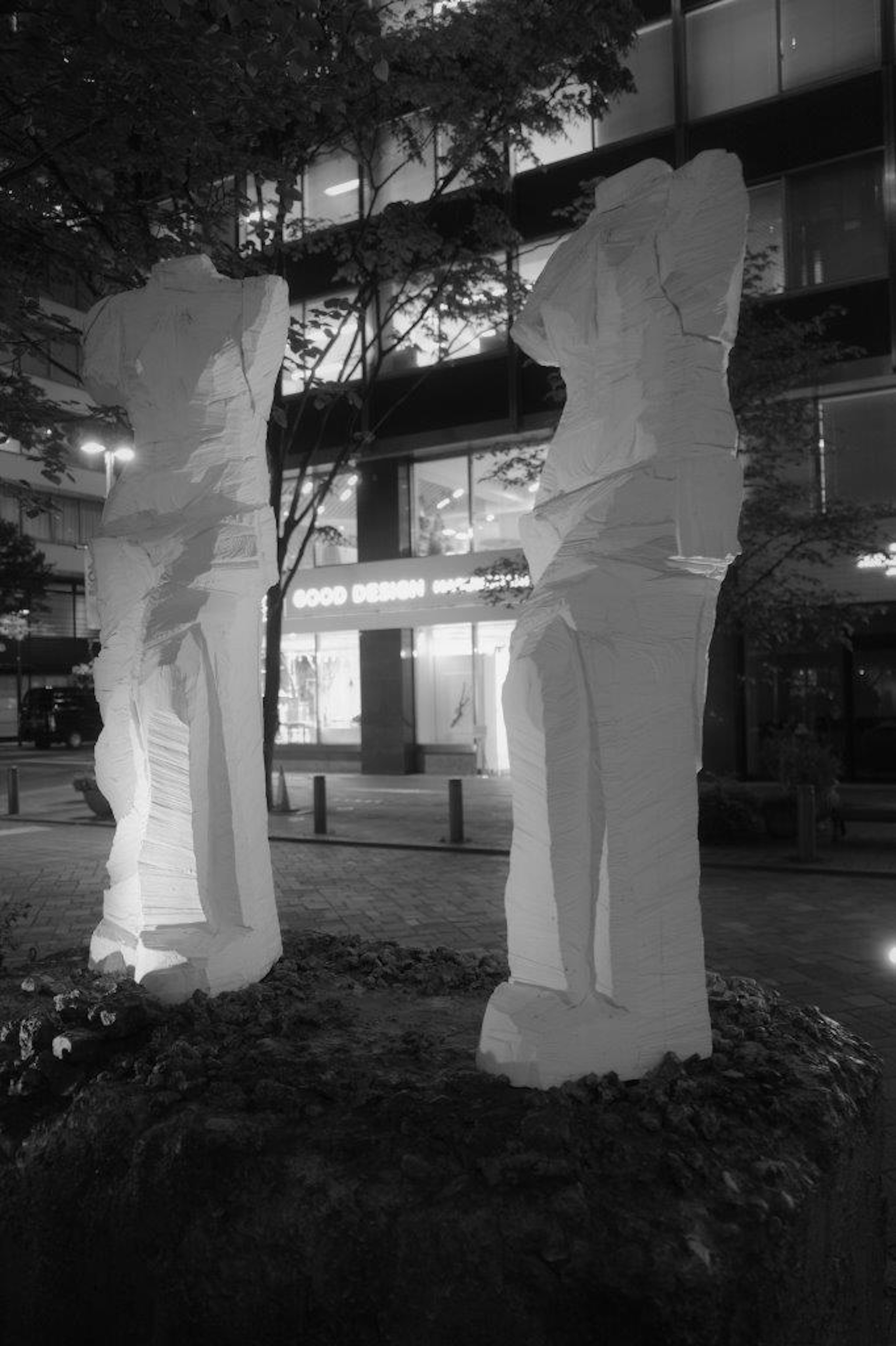 Due sculture bianche che si ergono in un ambiente urbano di notte