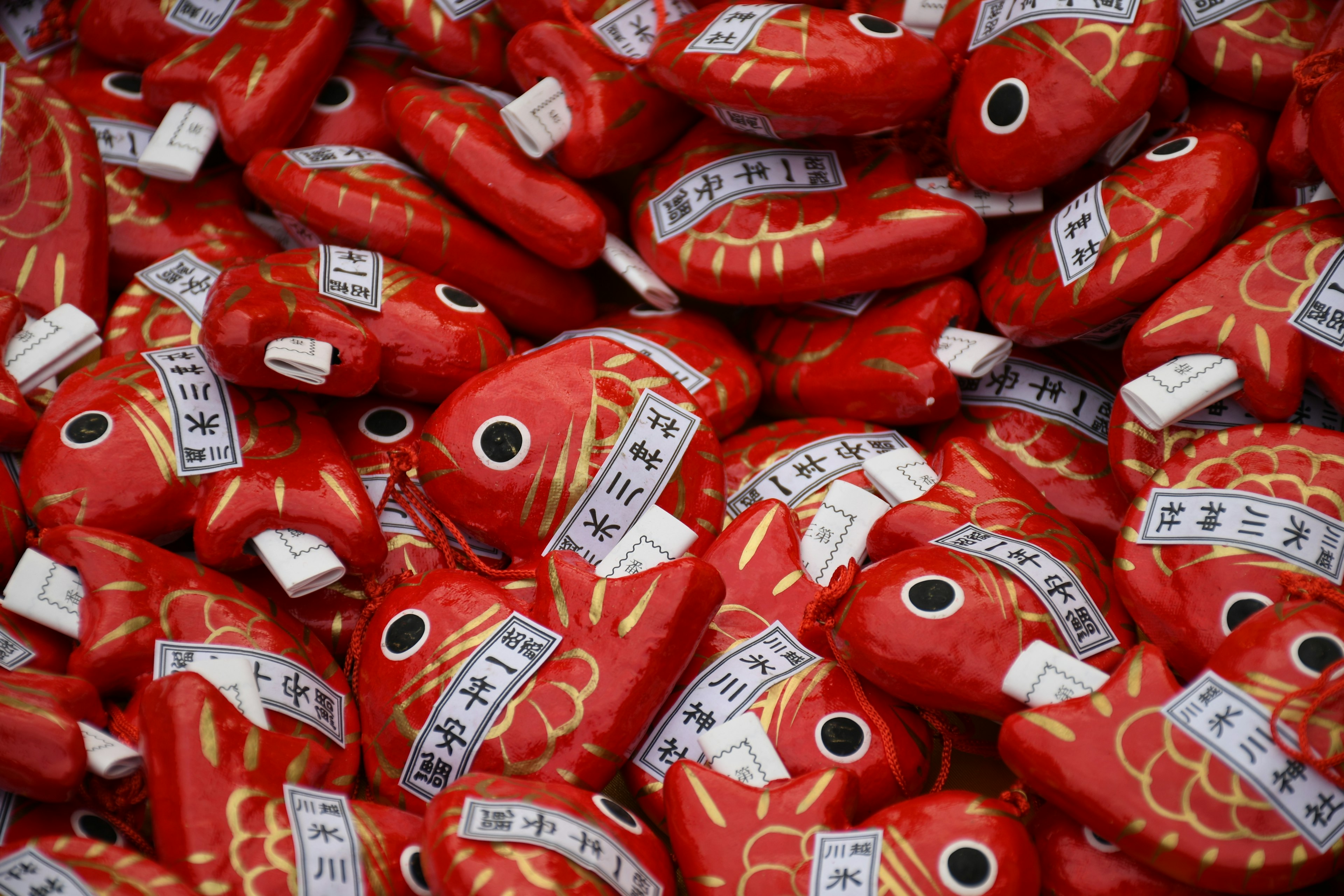 Un montón de talismanes en forma de pez rojo con inscripciones