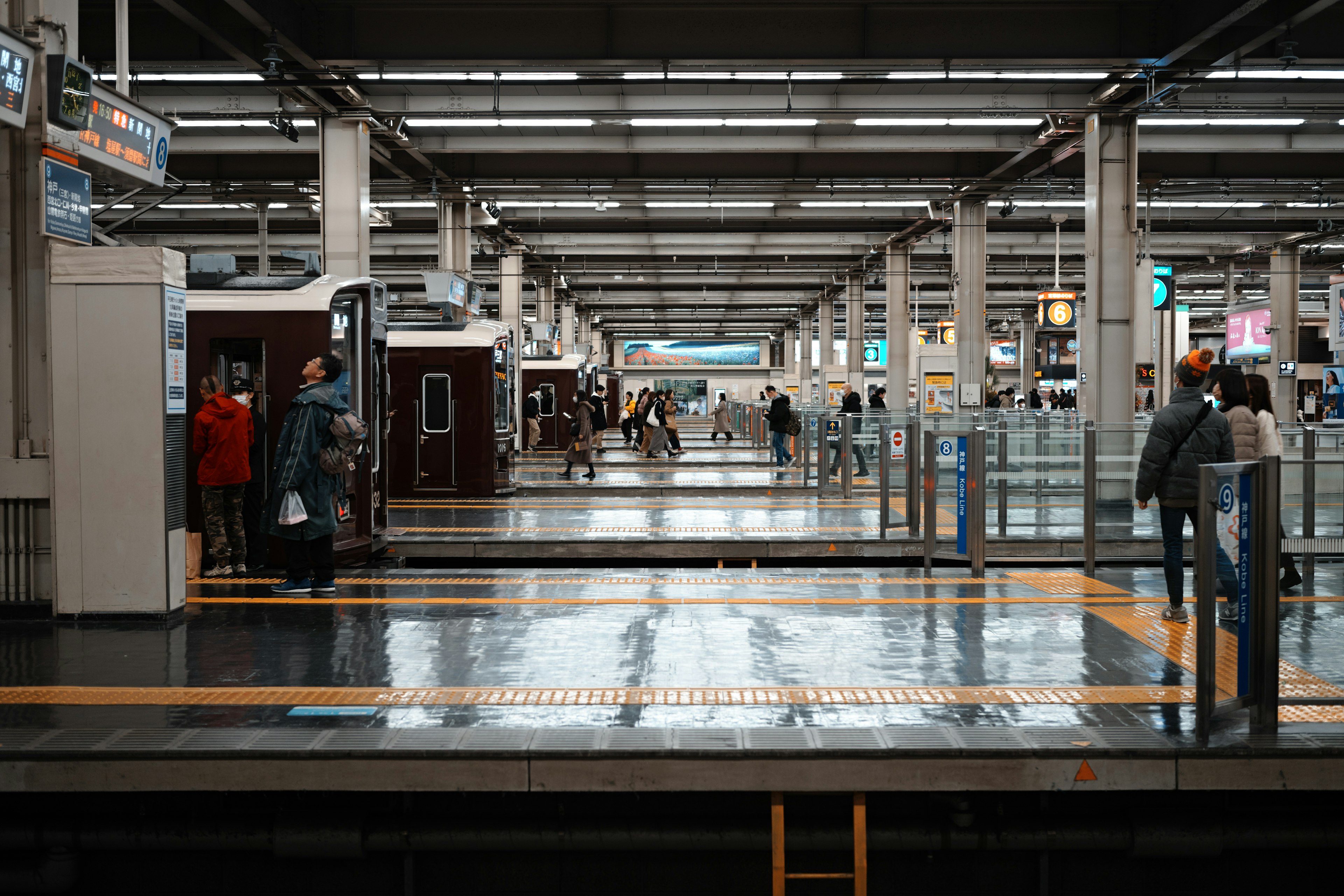 Plataforma de tren tranquila con personas y suelo reflectante