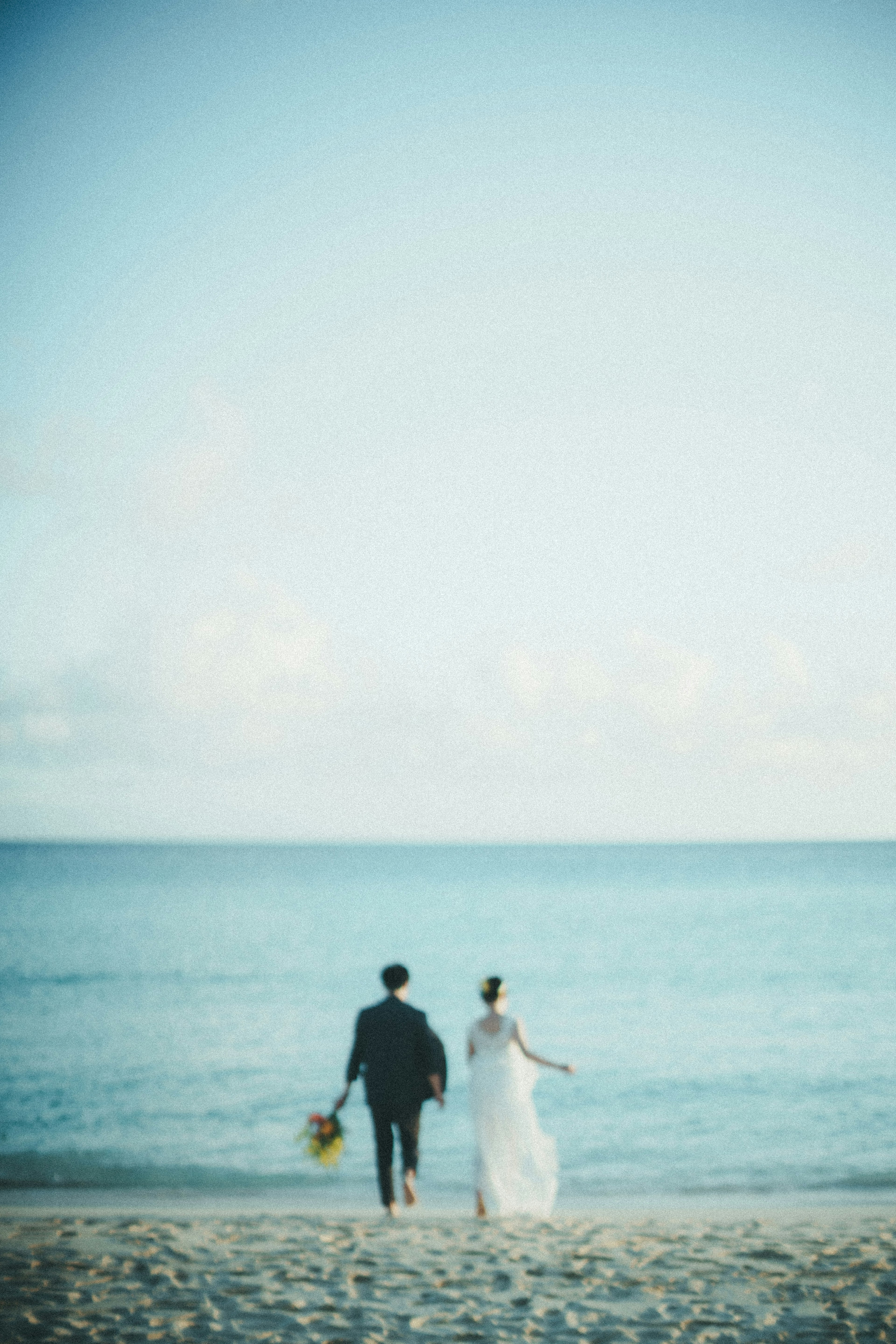 Couple walking along the beach with ocean backdrop