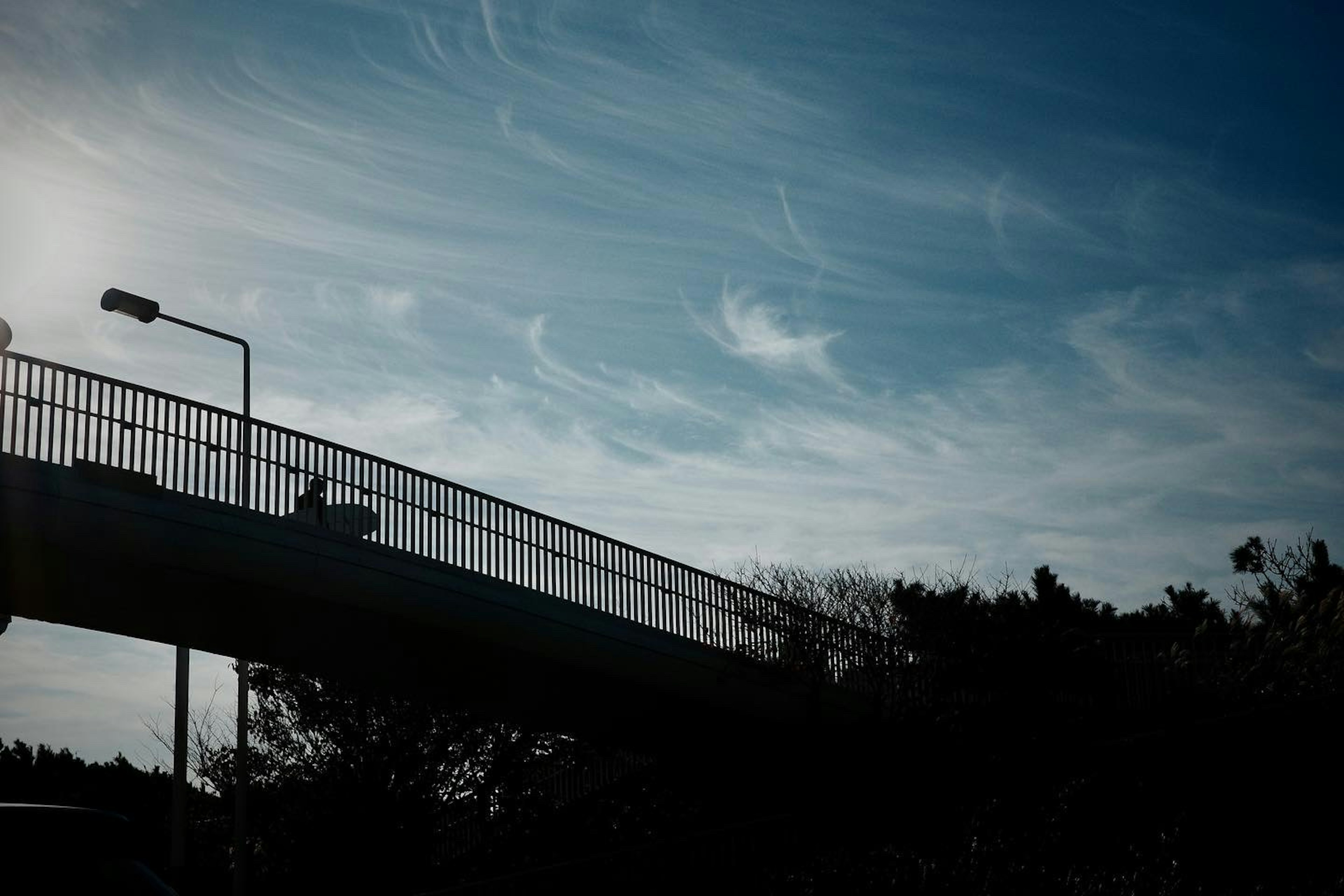 Silhouette of a bridge against a blue sky