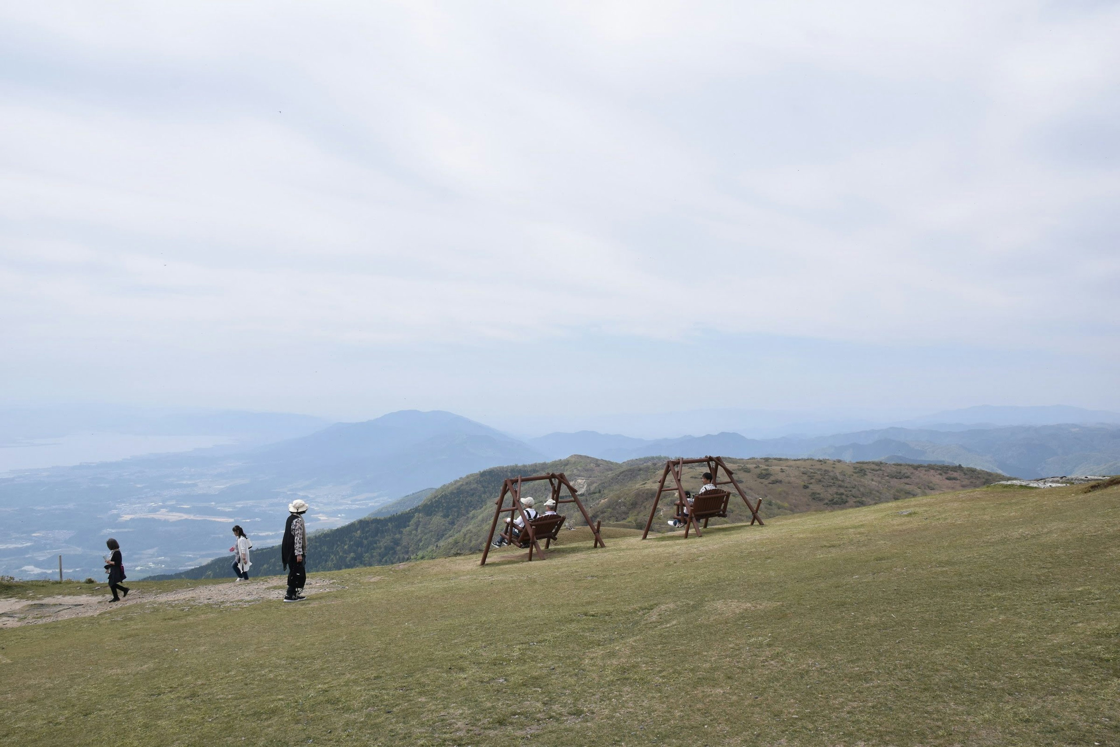 Des balançoires sur une colline herbeuse avec des gens profitant de la vue