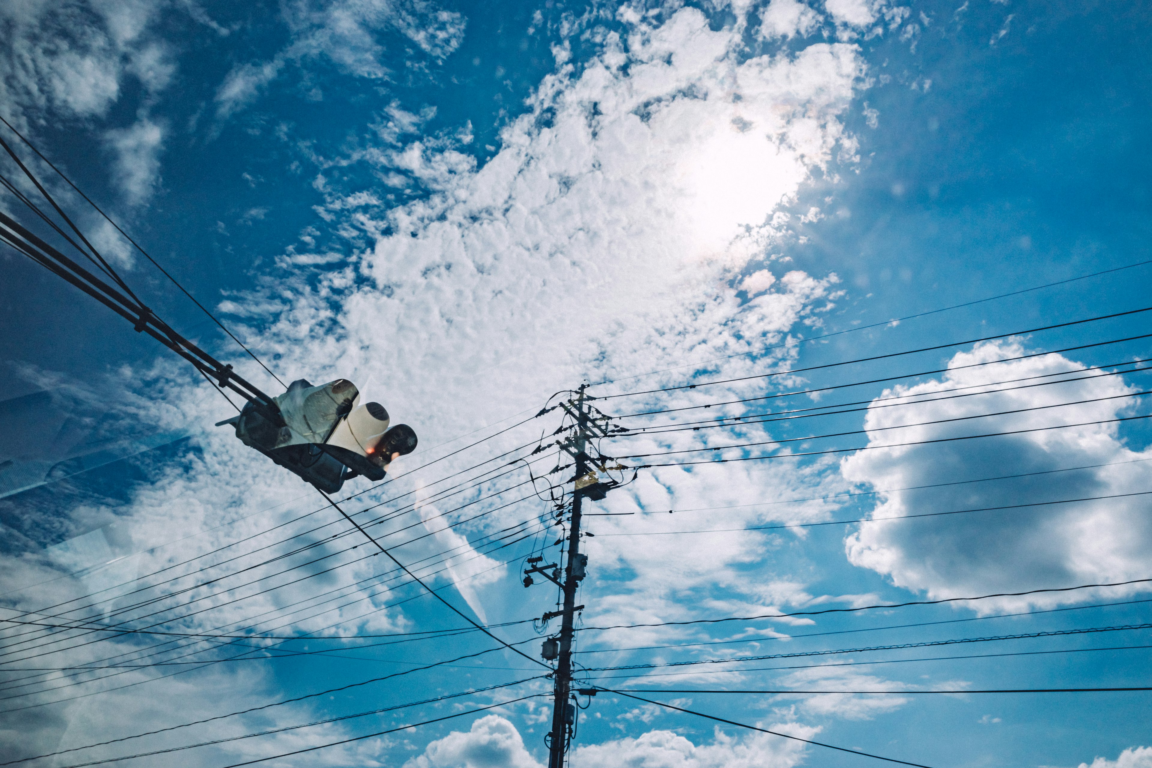 青空と白い雲が広がる背景に電柱が立っている