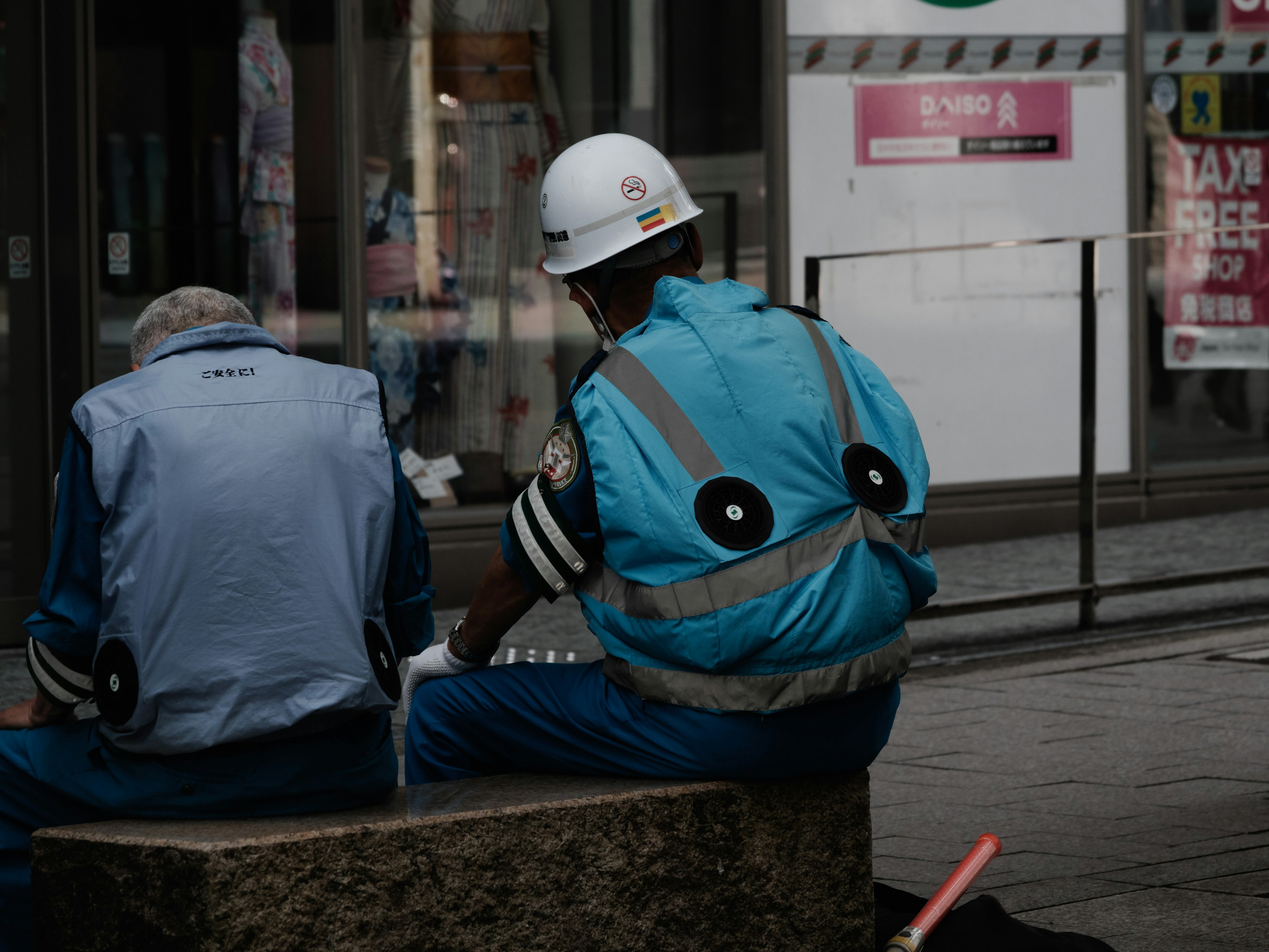 Deux ouvriers en uniformes bleus assis de dos