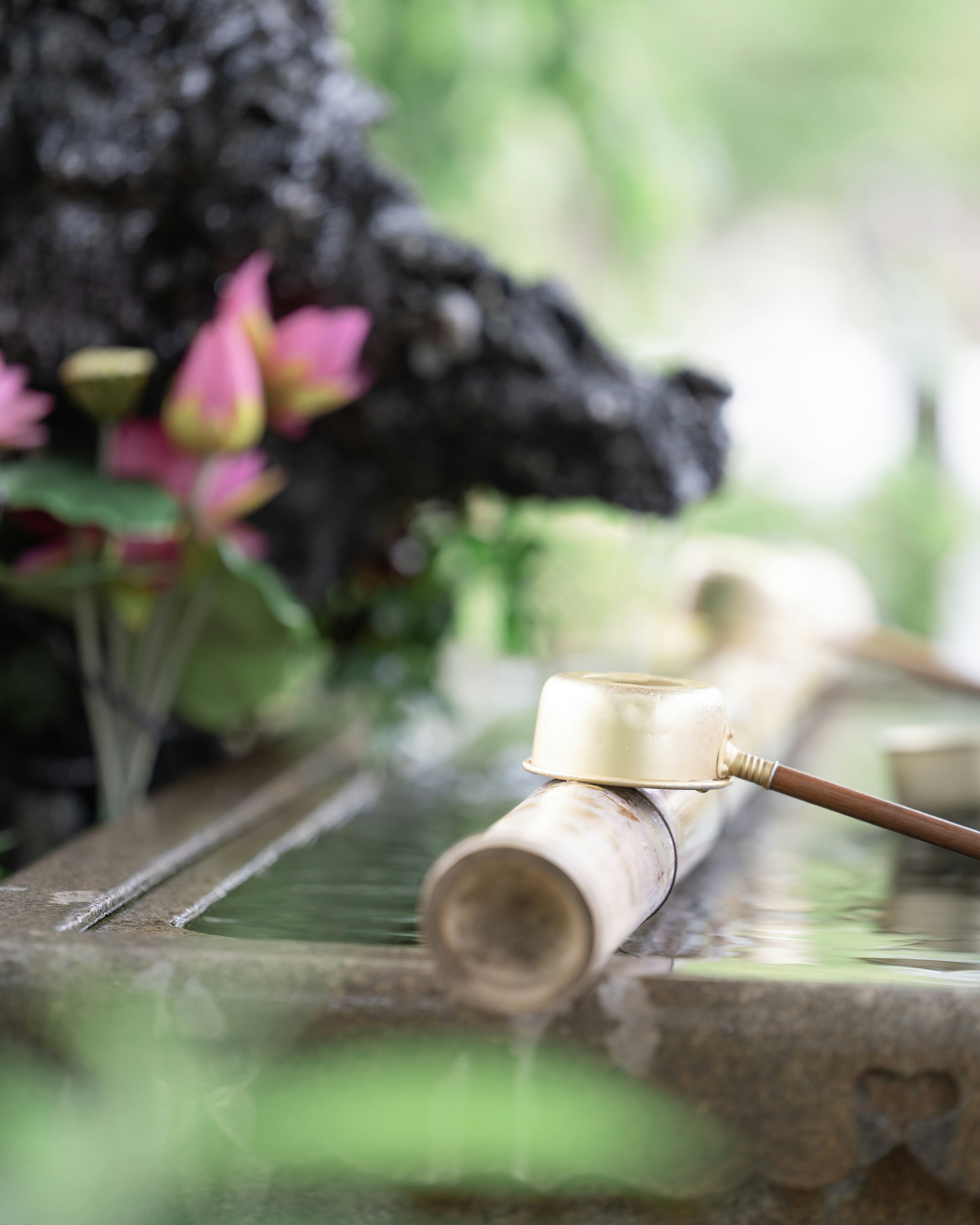 Bamboo water basin with flowers in a tranquil garden setting