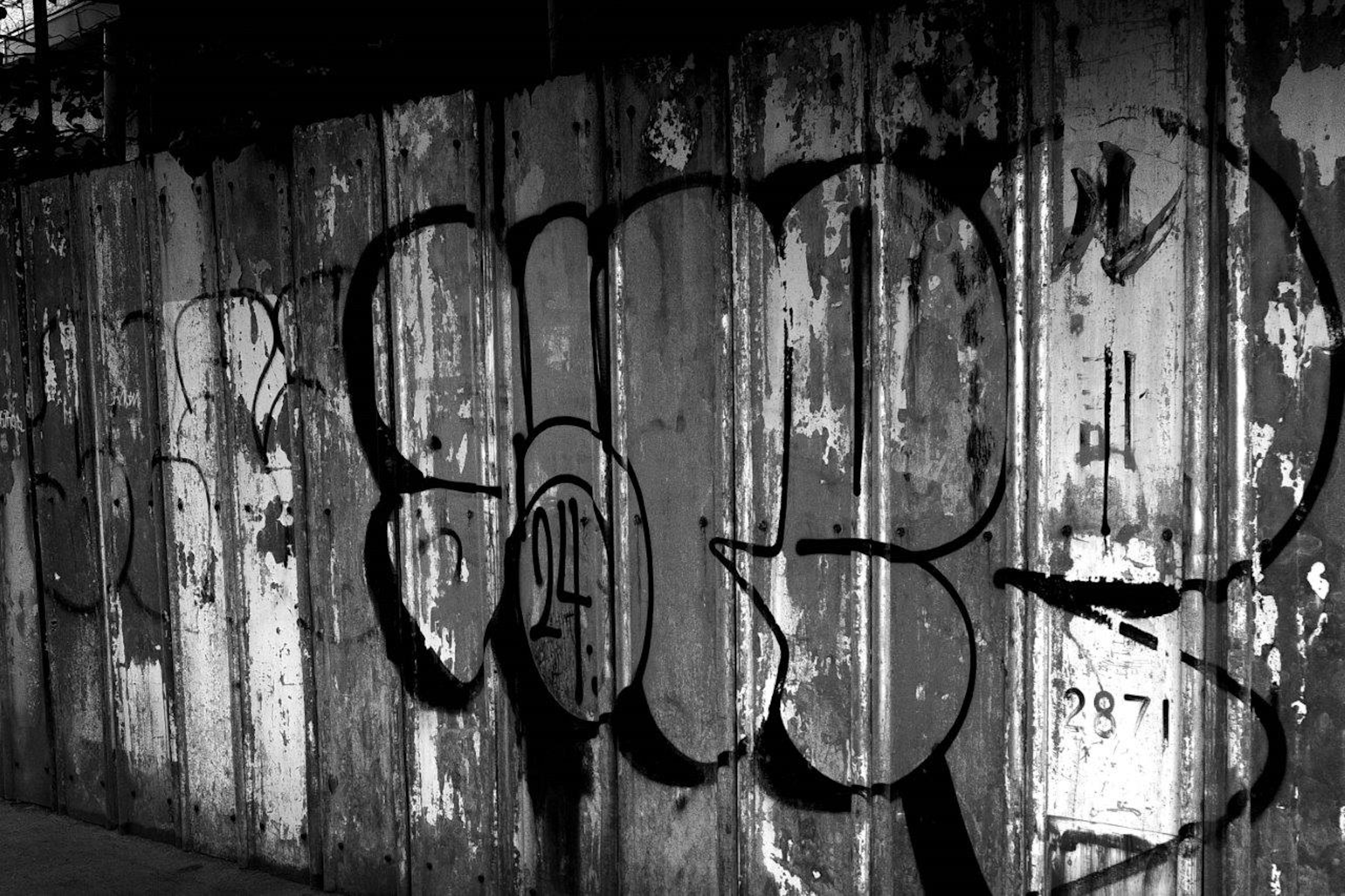 Black and white street art graffiti on an old metal wall