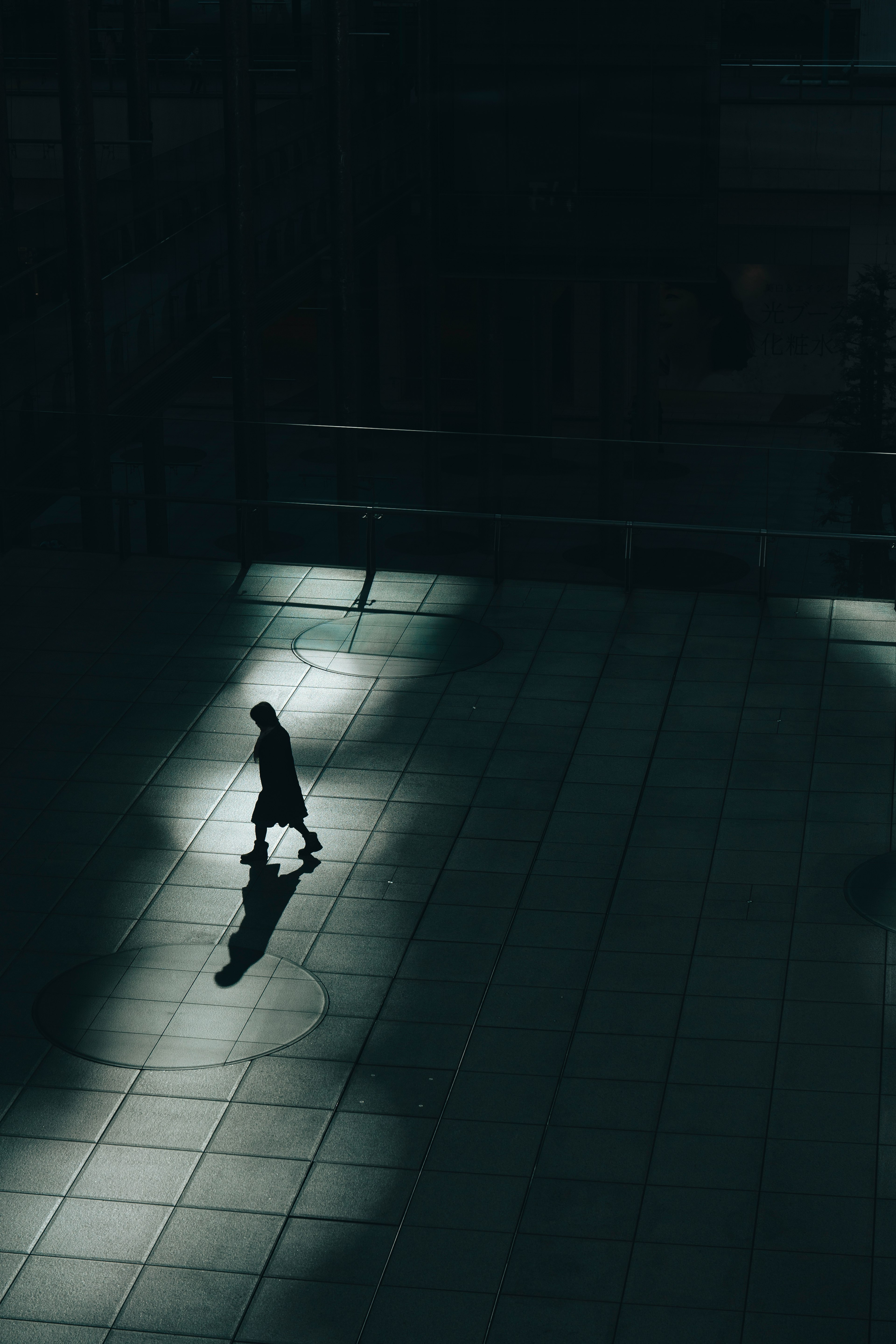 Silhouette of a person walking in shadows on a dark background