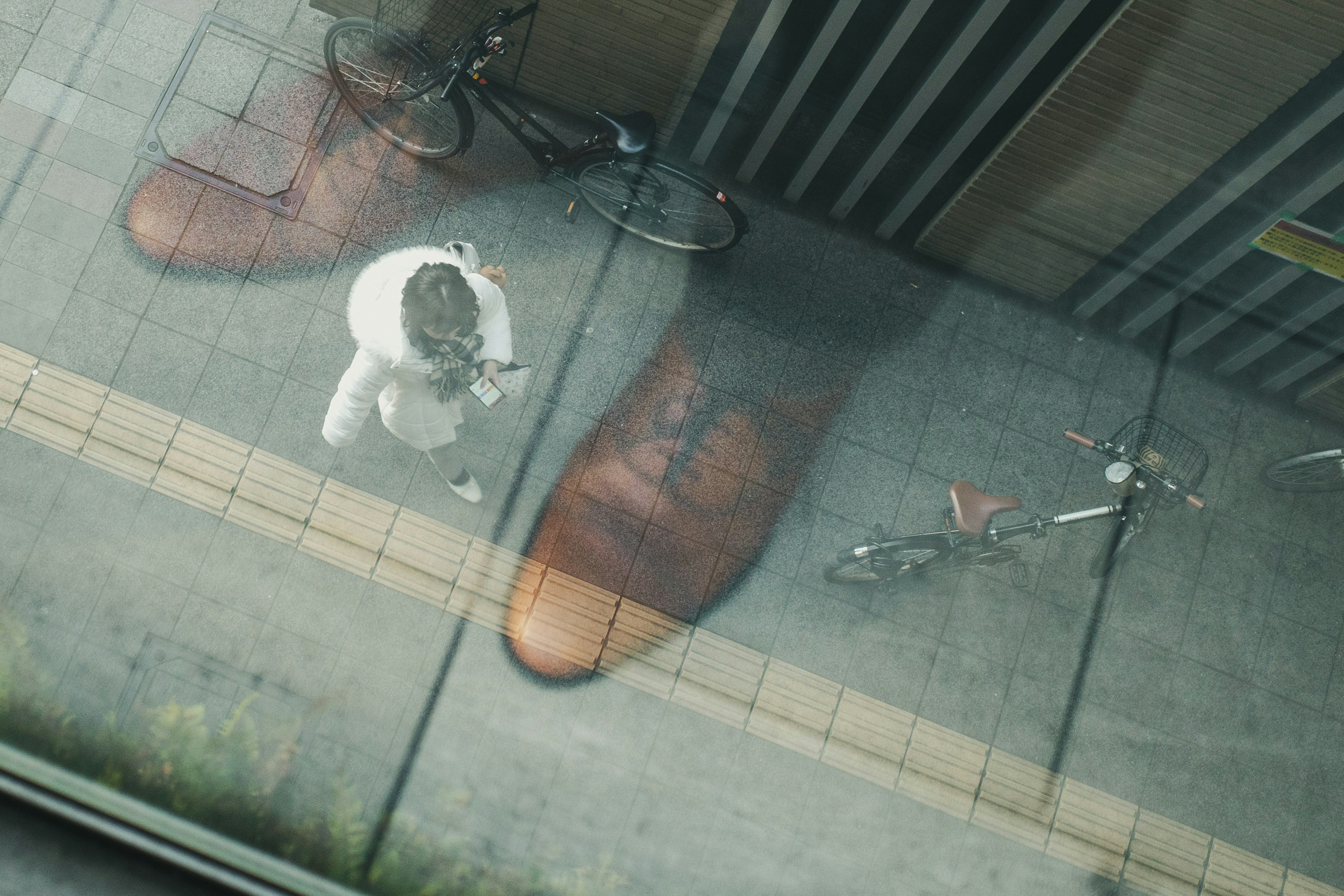 Reflejo de una persona de pie cerca de zapatos sobredimensionados con bicicletas cerca