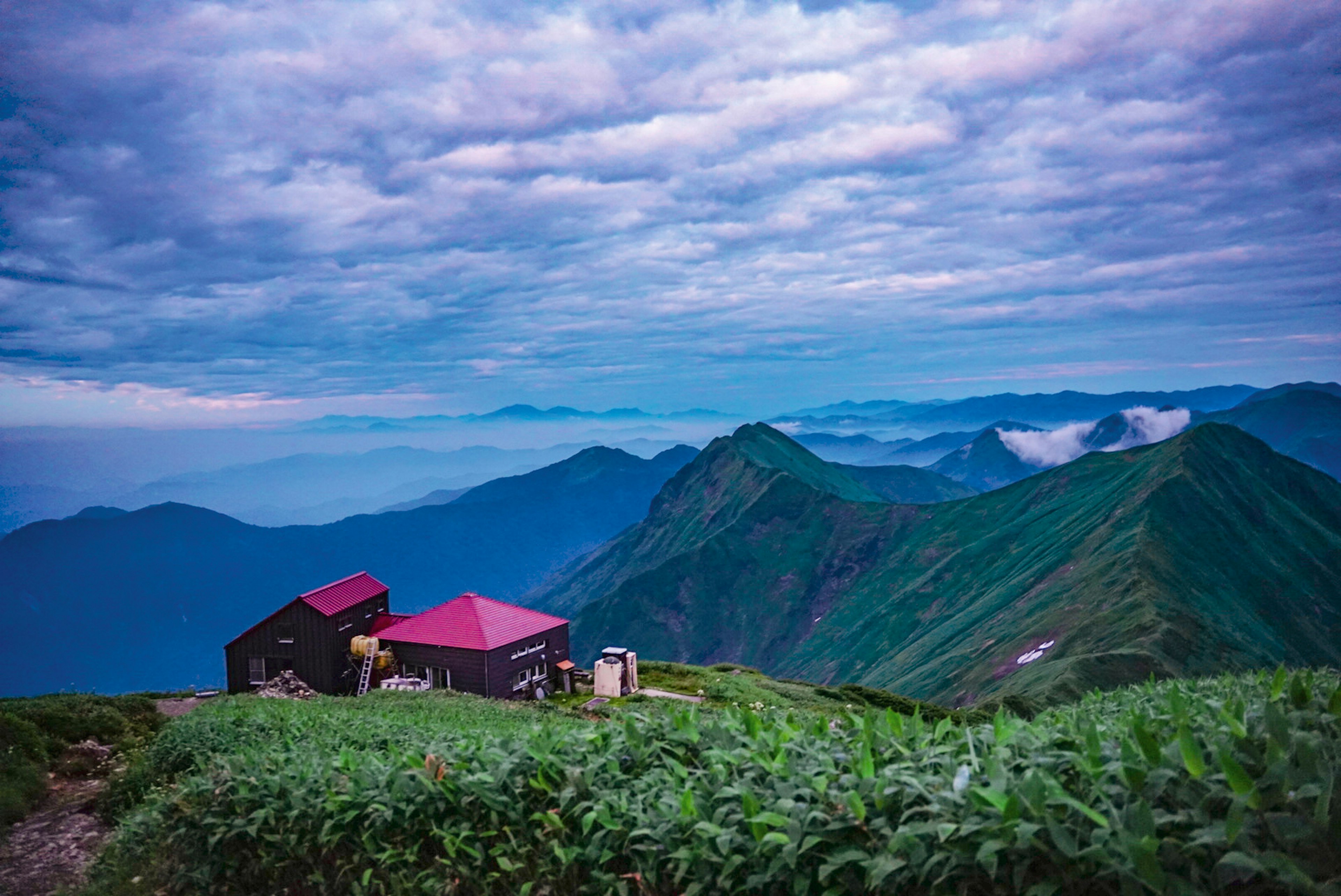 青い山々と雲に囲まれた小屋の風景