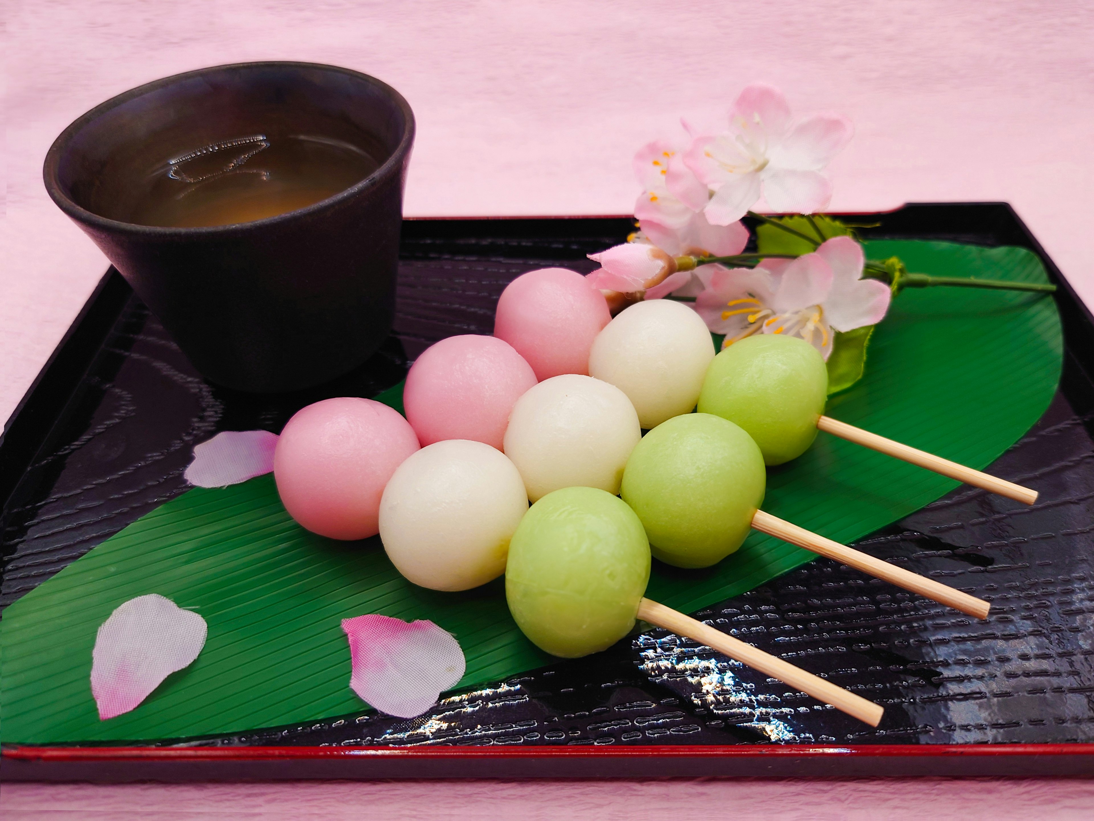 Brochetas de dango coloridas con té en una bandeja decorativa