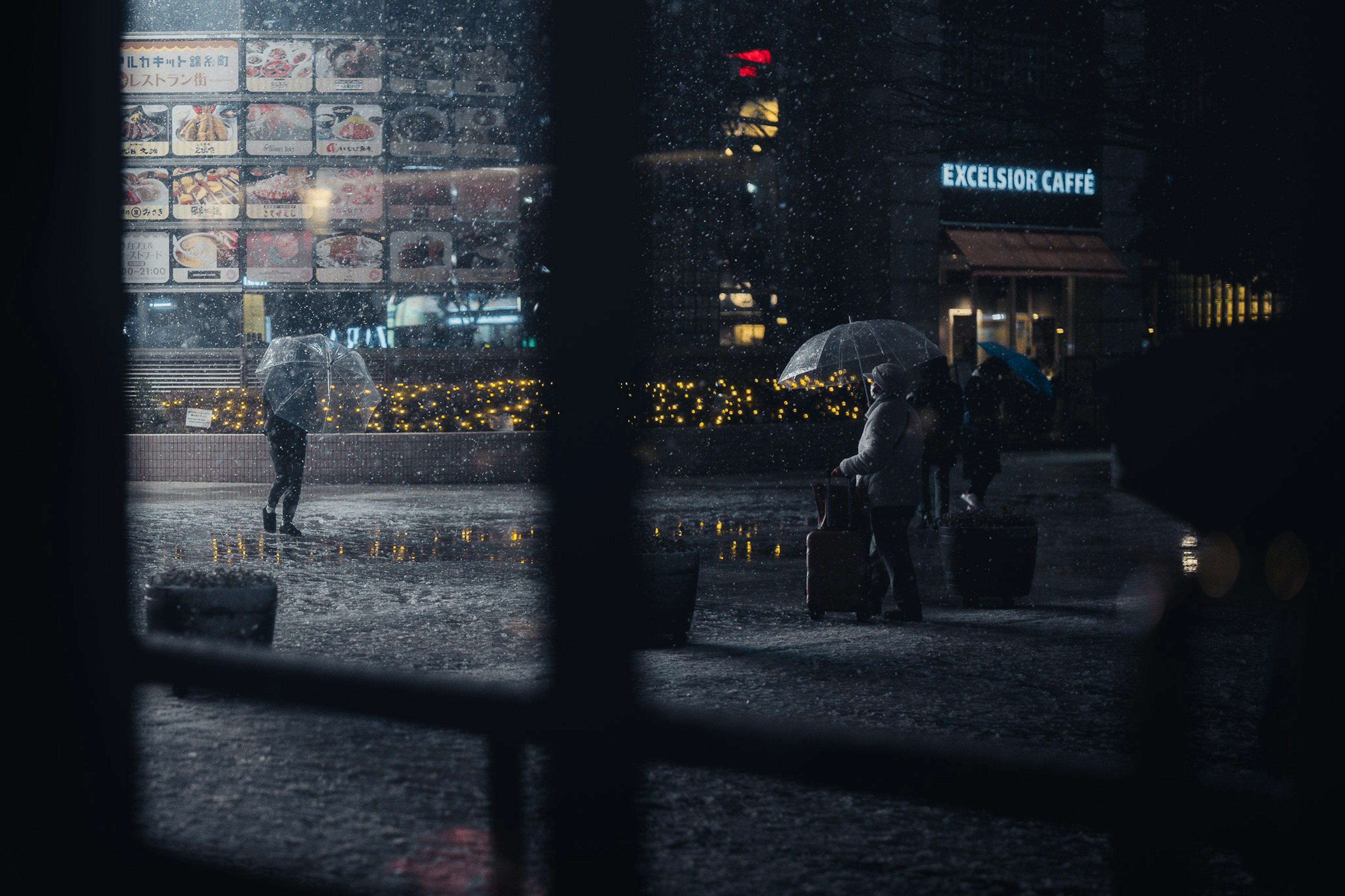 Scène de rue nocturne avec des personnes marchant sous des parapluies sous la pluie