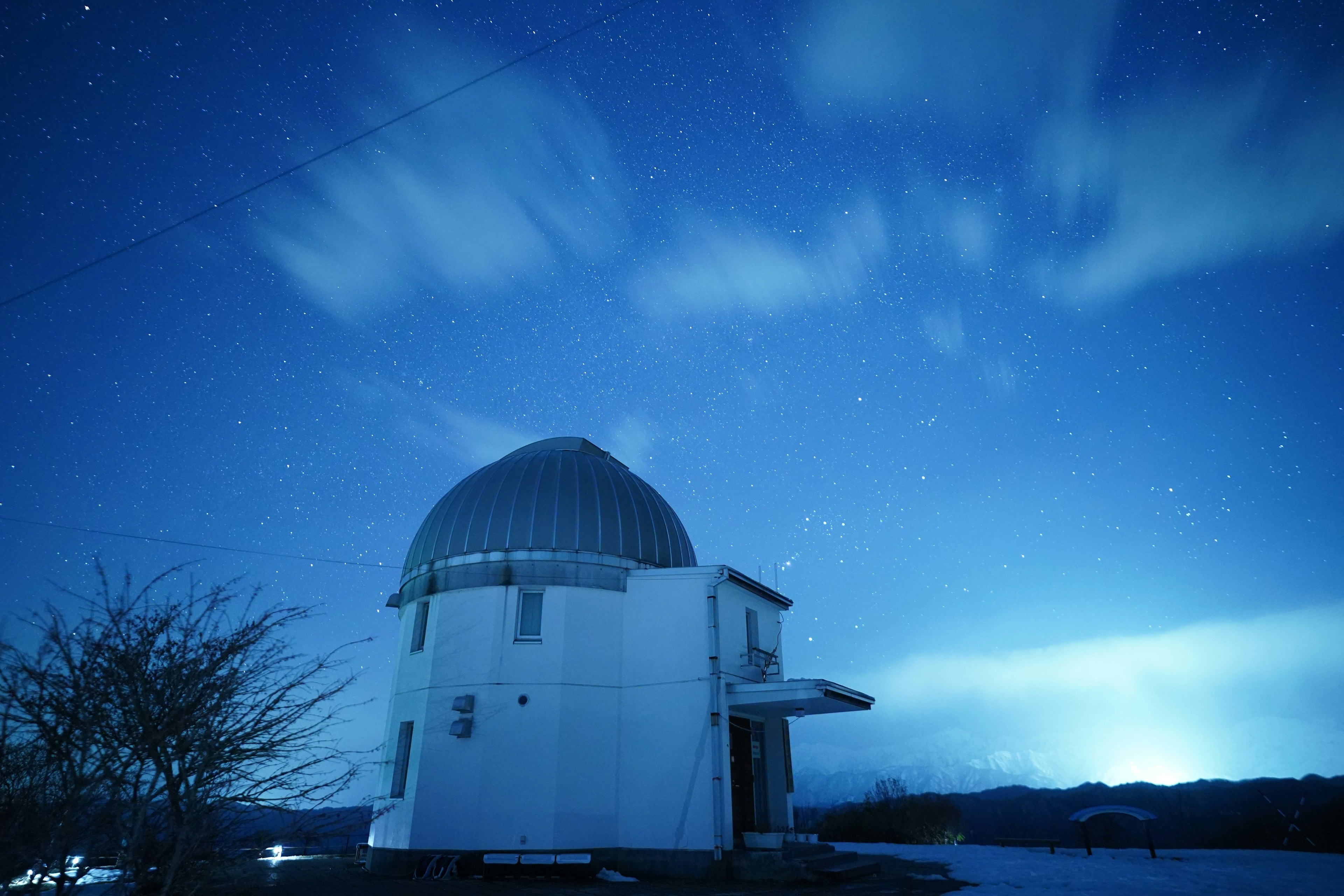 Imagen de un observatorio bajo un cielo nocturno azul con estrellas brillantes y nubes