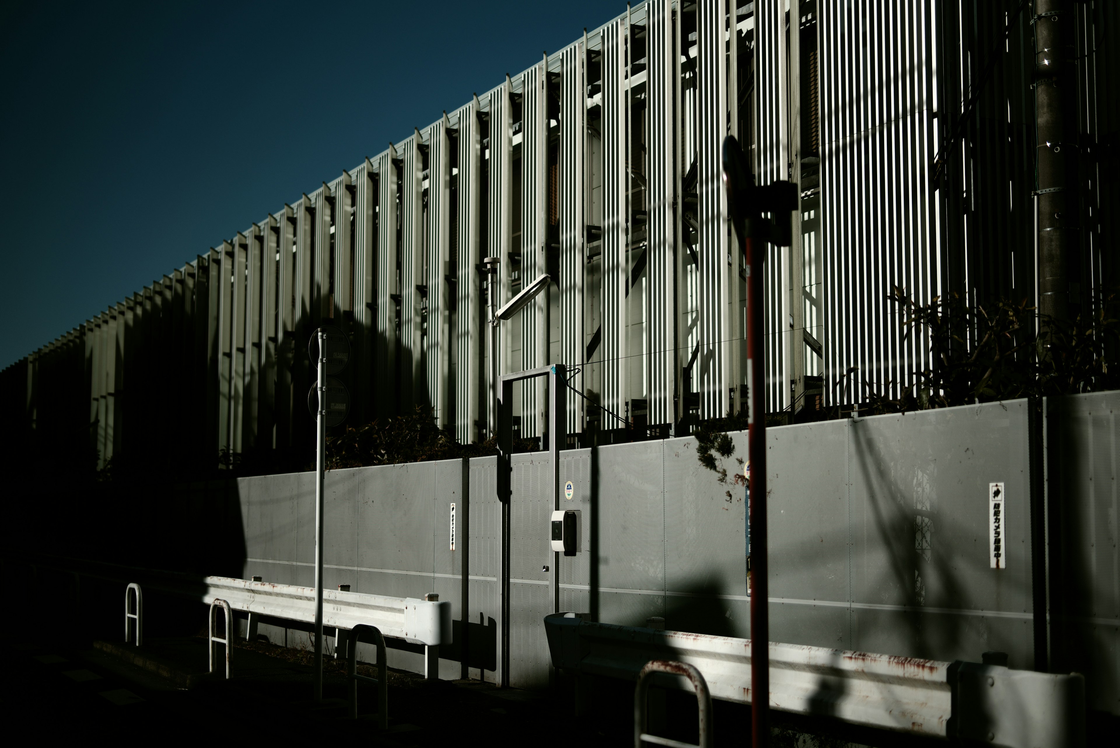 Photo d'une clôture industrielle avec des ombres sur le mur