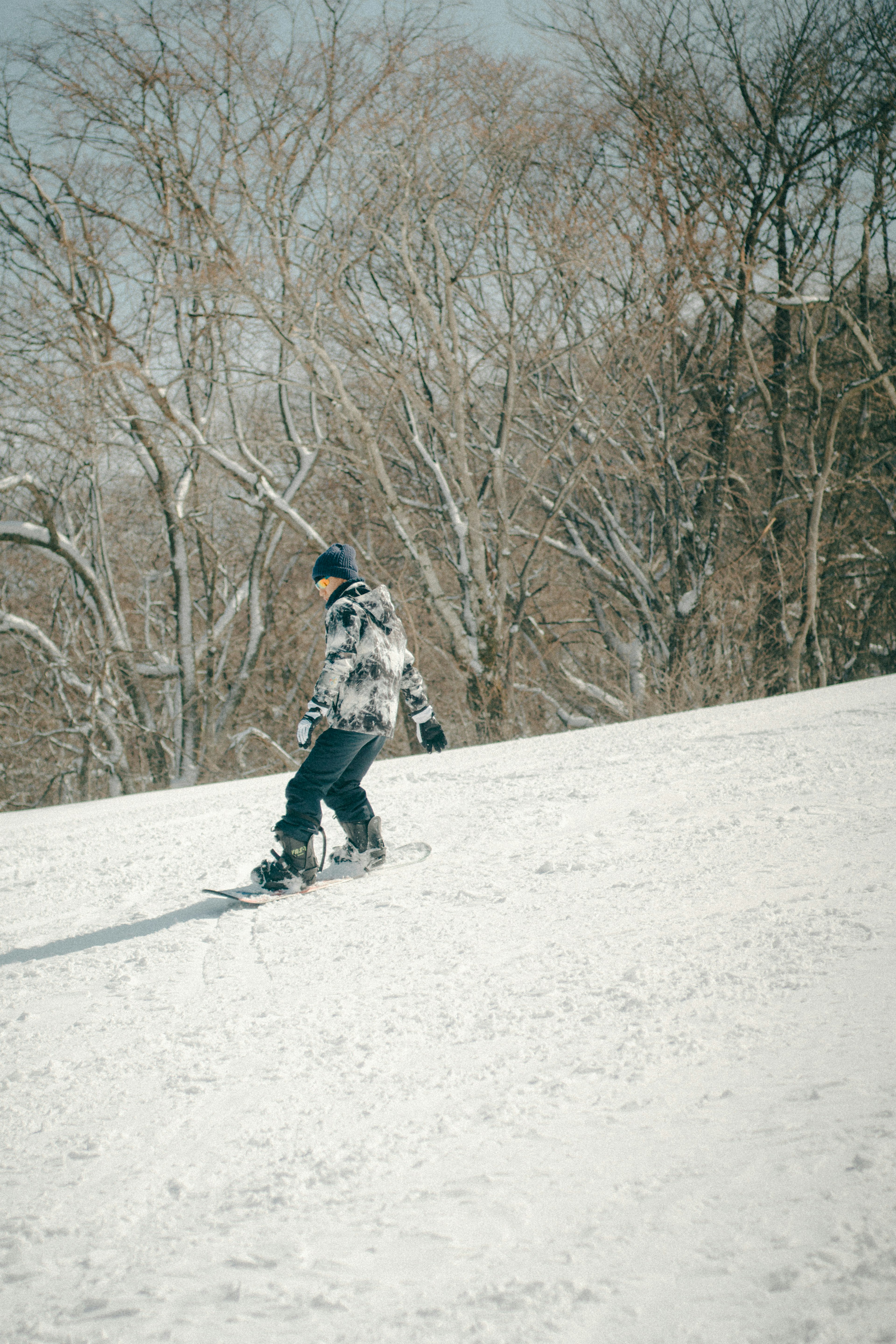 Ein männlicher Snowboarder, der einen verschneiten Hang hinuntergleitet